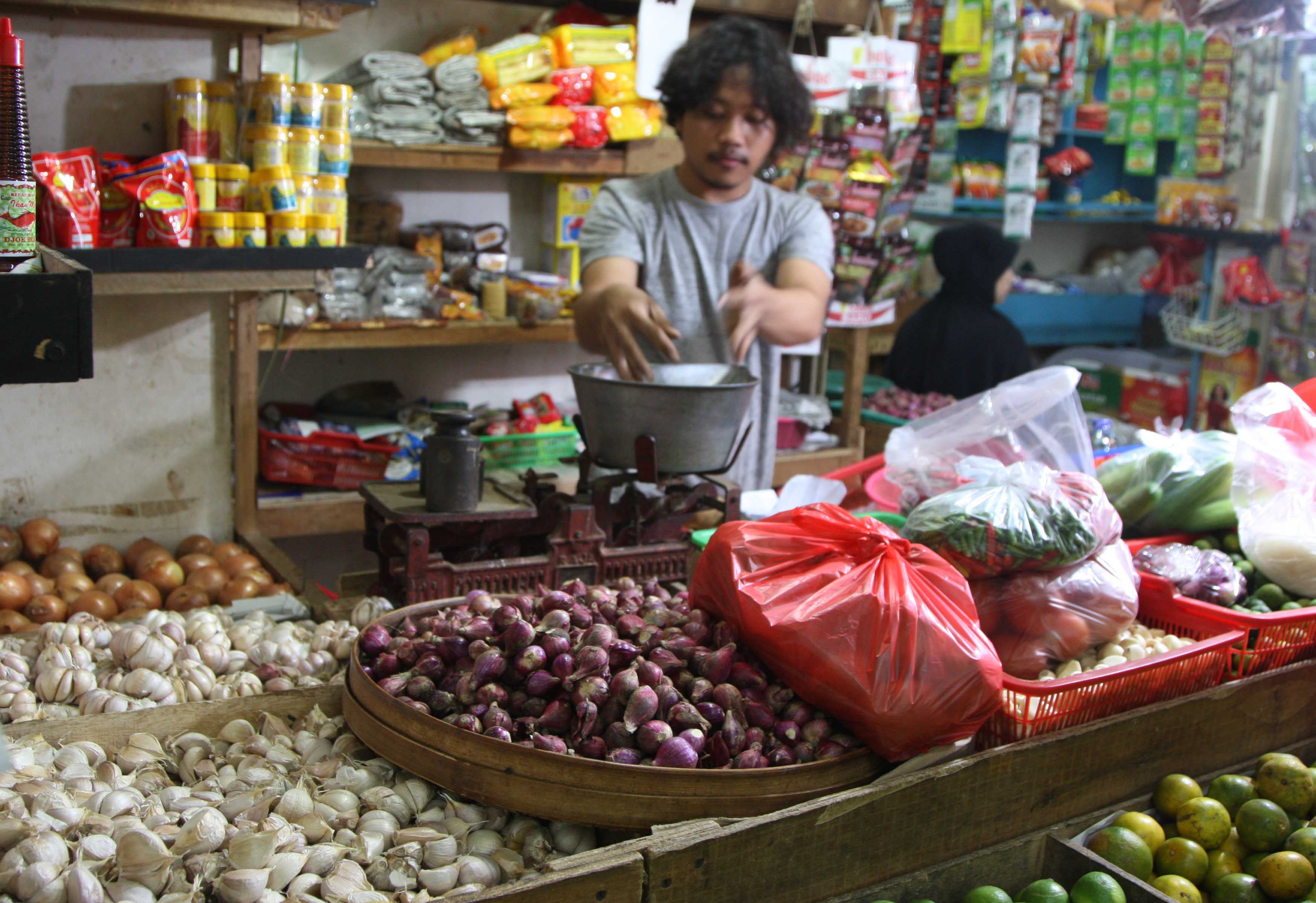 Pedagang bahan pokok sedang melayani pembeli.