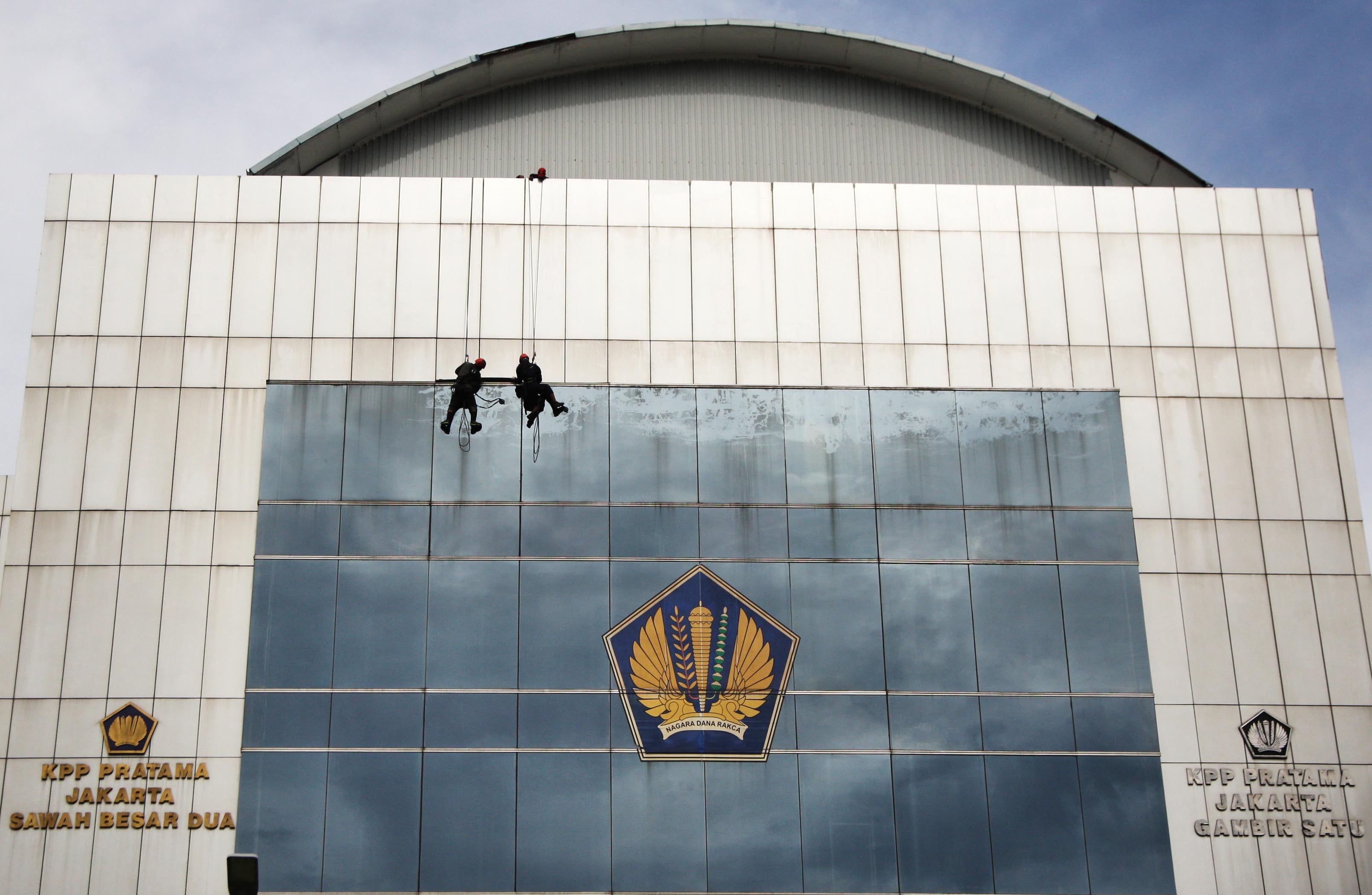 Petugas membersihkan gedung Kantor Pelayanan Pajak di wilayah Jakarta.