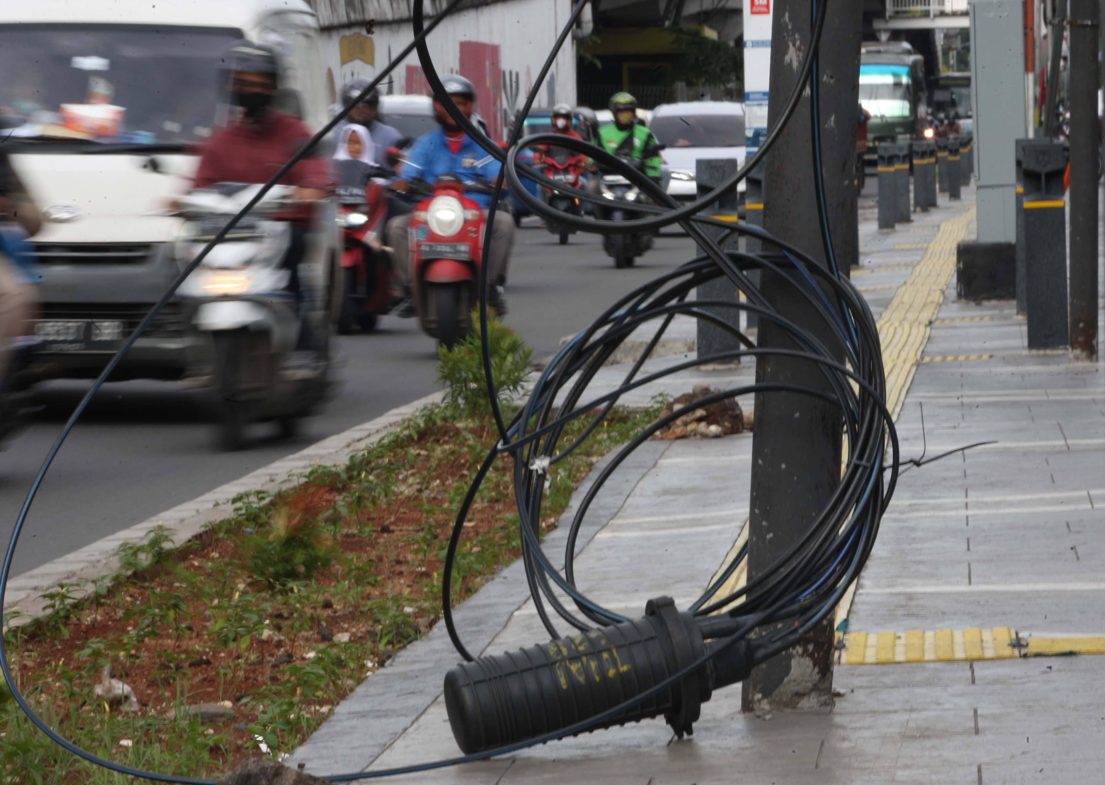Kabel optik dari perusahaan penyedia jaringan utilitas yang mengganggu pengguna jalan