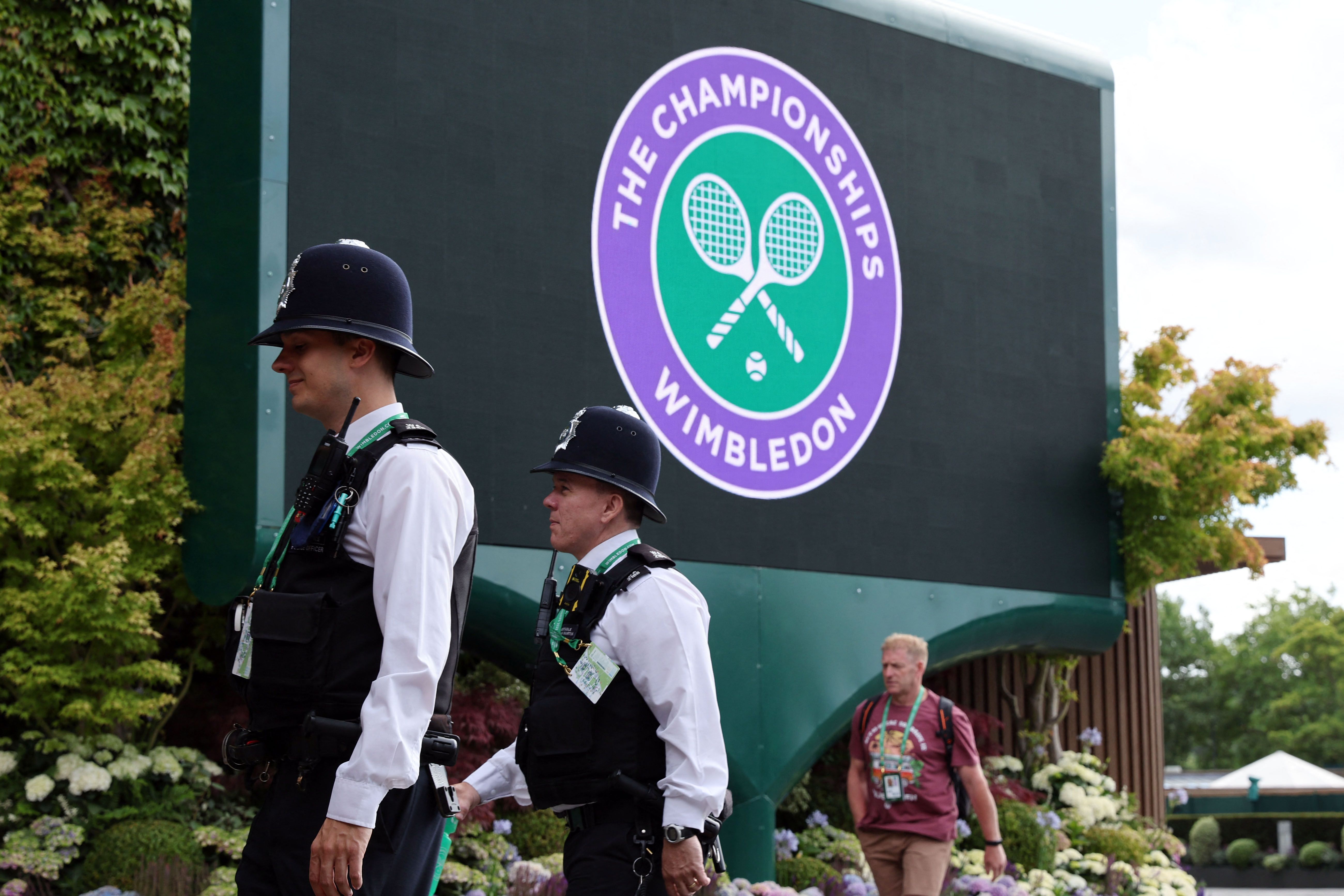 Dua polisi berjalan melintas di depan logo Wimbledon di All England Tennis Club di Wimbledon, dekat London.