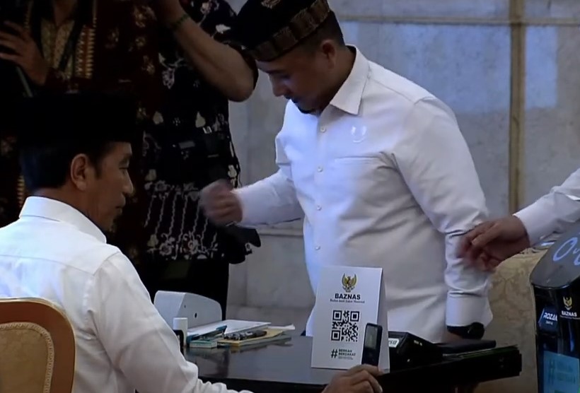 Presiden Jokowi (kiri) membayar zakat melalui mesin yang disediakan Baznas di Istana Negara, Jakarta, Selasa (28/3).