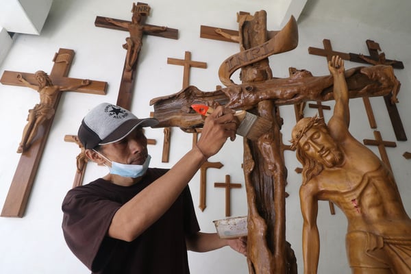 Perajin melakukan proses pewarnaan patung salib berbahan baku kayu jati.