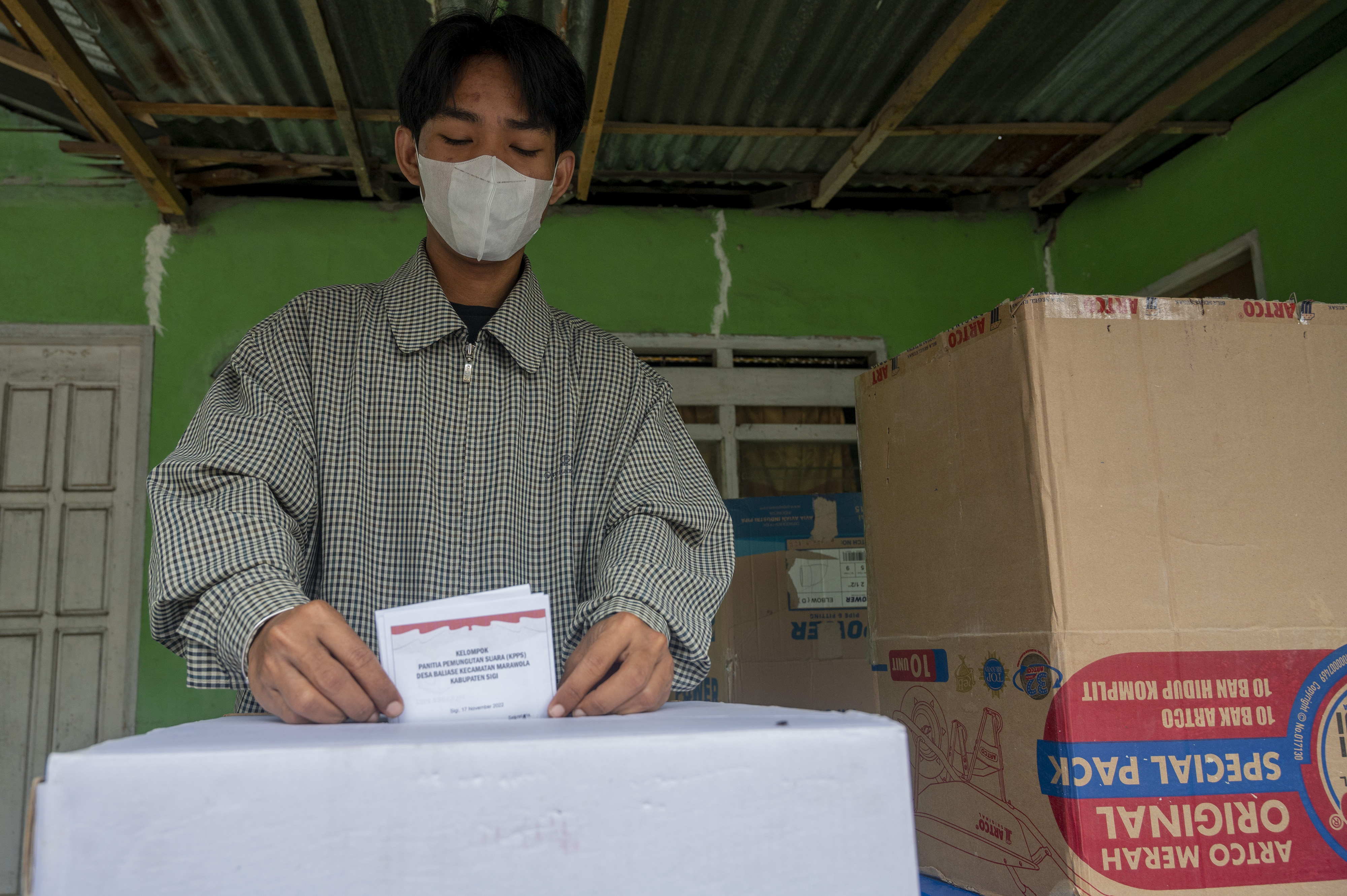 Warga memasukan kertas suara ke dalam kotak suara.