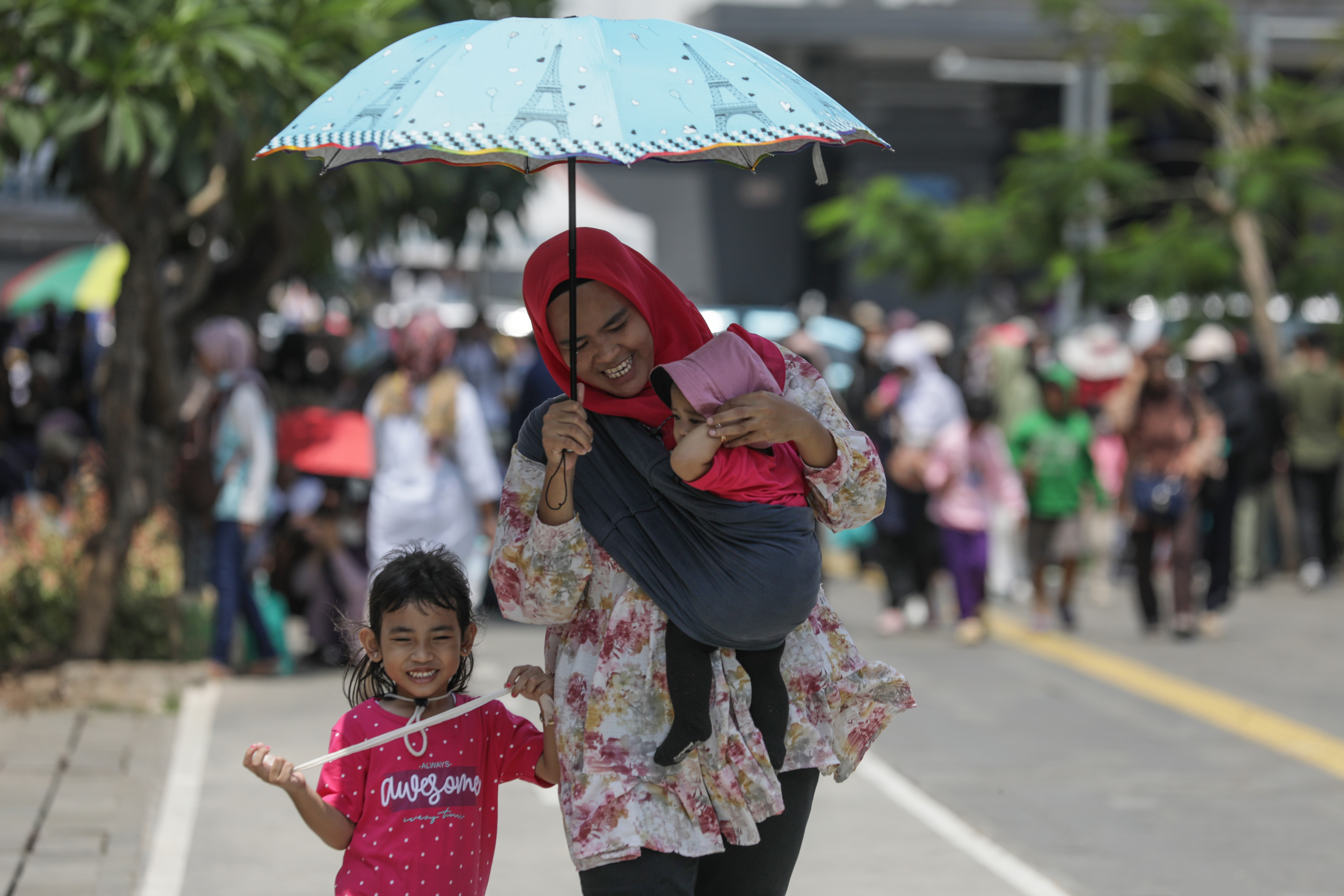 Pengunjung menggunakan payung untuk berlindung dari sengatan sinar matahari saat mengunjungi tempat wisata Kota Tua, Jakarta, Selasa (25/4).