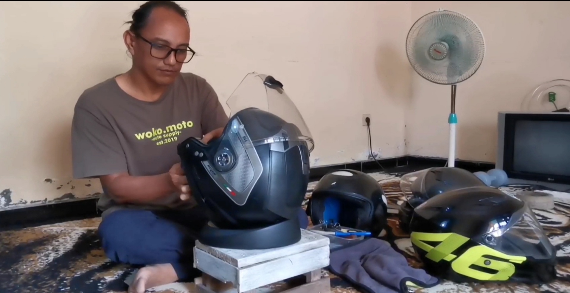Woko Moto sedang memperbaiki helm milik pelanggannya.