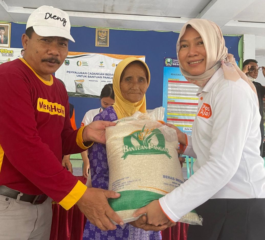 Direktur Bisnis Kurir dan Logistik Pos Indonesia Siti Choiriana (kanan) menyerahkan bantuan pangan beras secara simbolis di Magetan, Jatim.