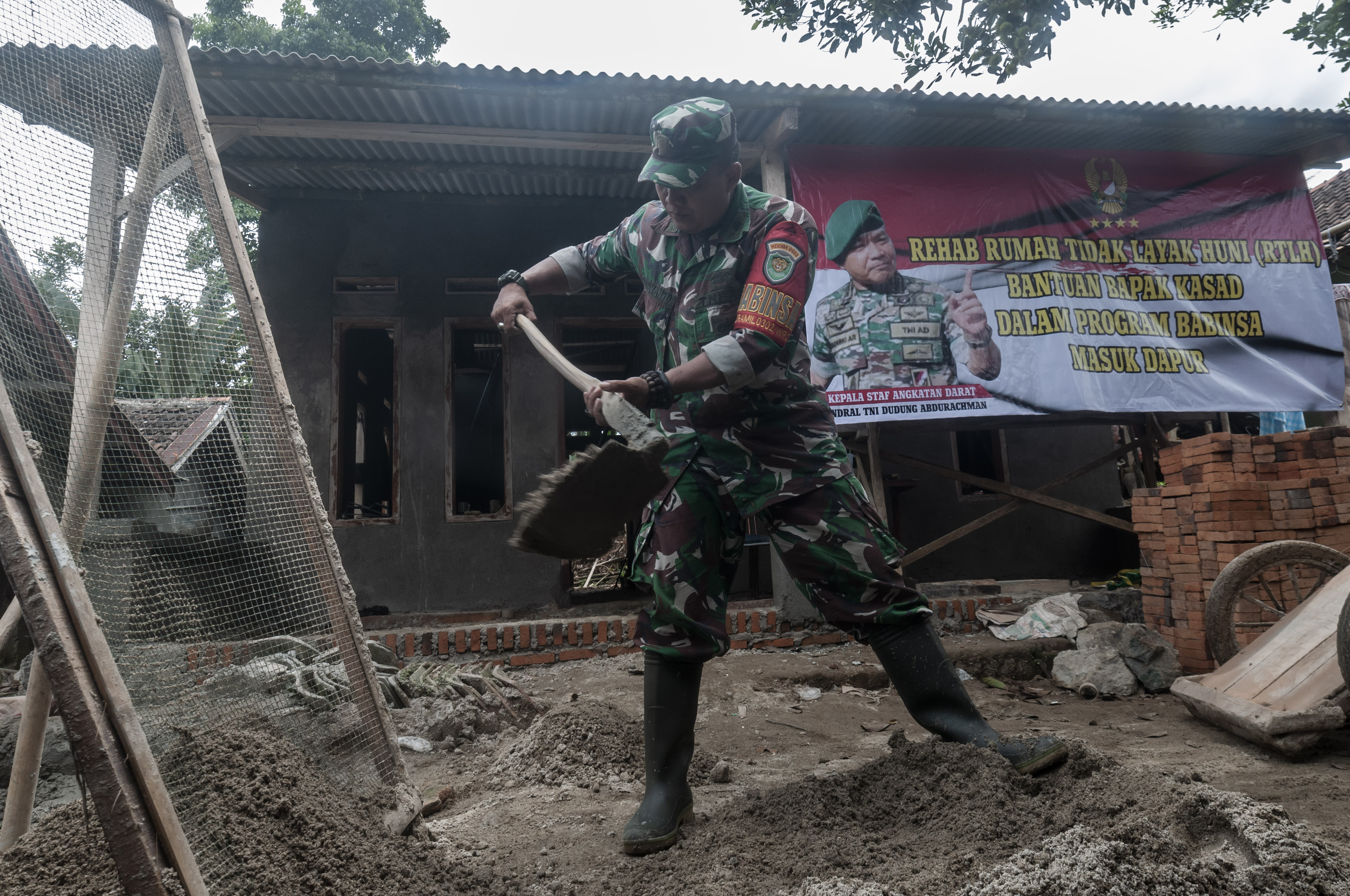 Seorang prajurit TNI-AD tengah membantu bedah rumah tidak layak huni