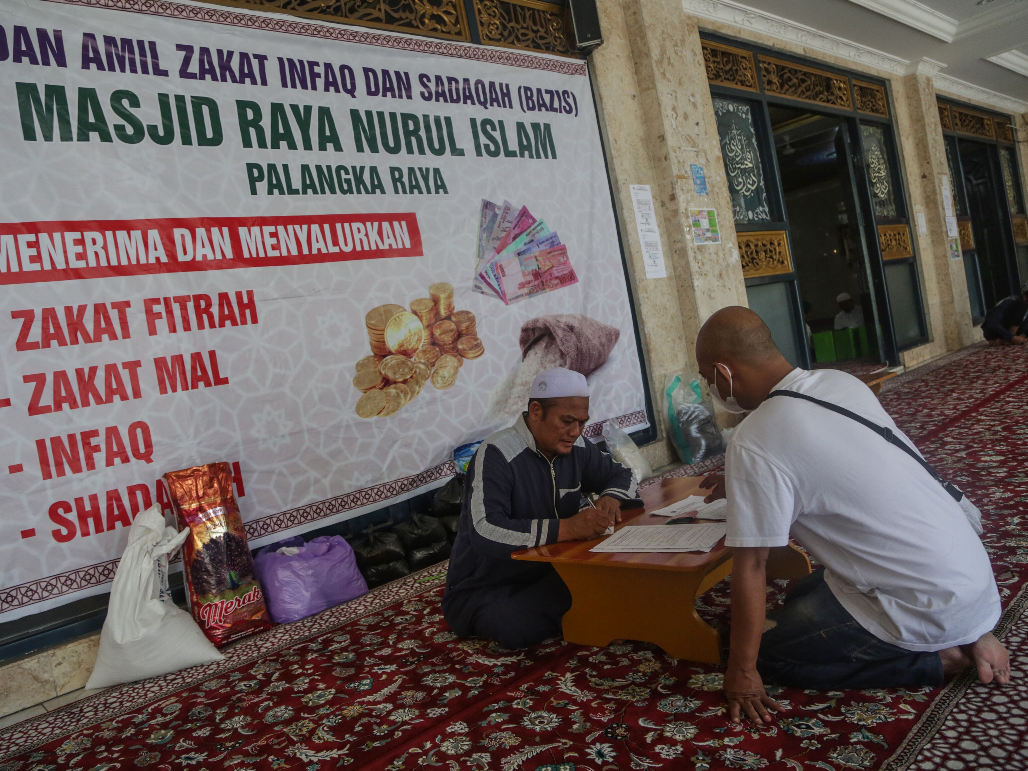 Panitia amil zakat menerima zakat fitrah dari warga di Masjid Raya Nurul Islam, Palangka Raya, Kalimantan Tengah.
