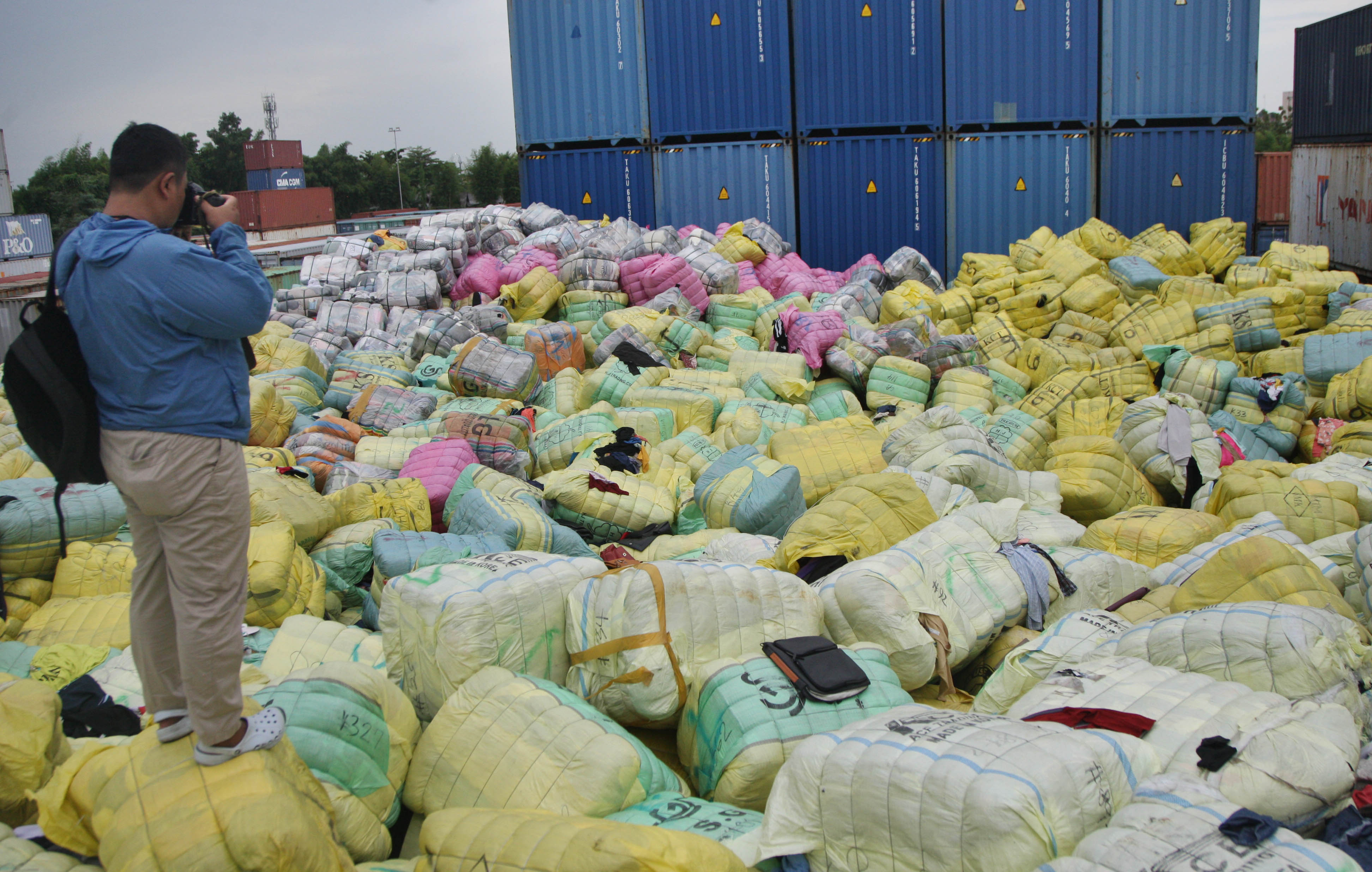 Seorang pewarta foto tengah memotret tumpukan ribuan bal pakaian bekas impor illegal yang disita Bea dan Cukai.