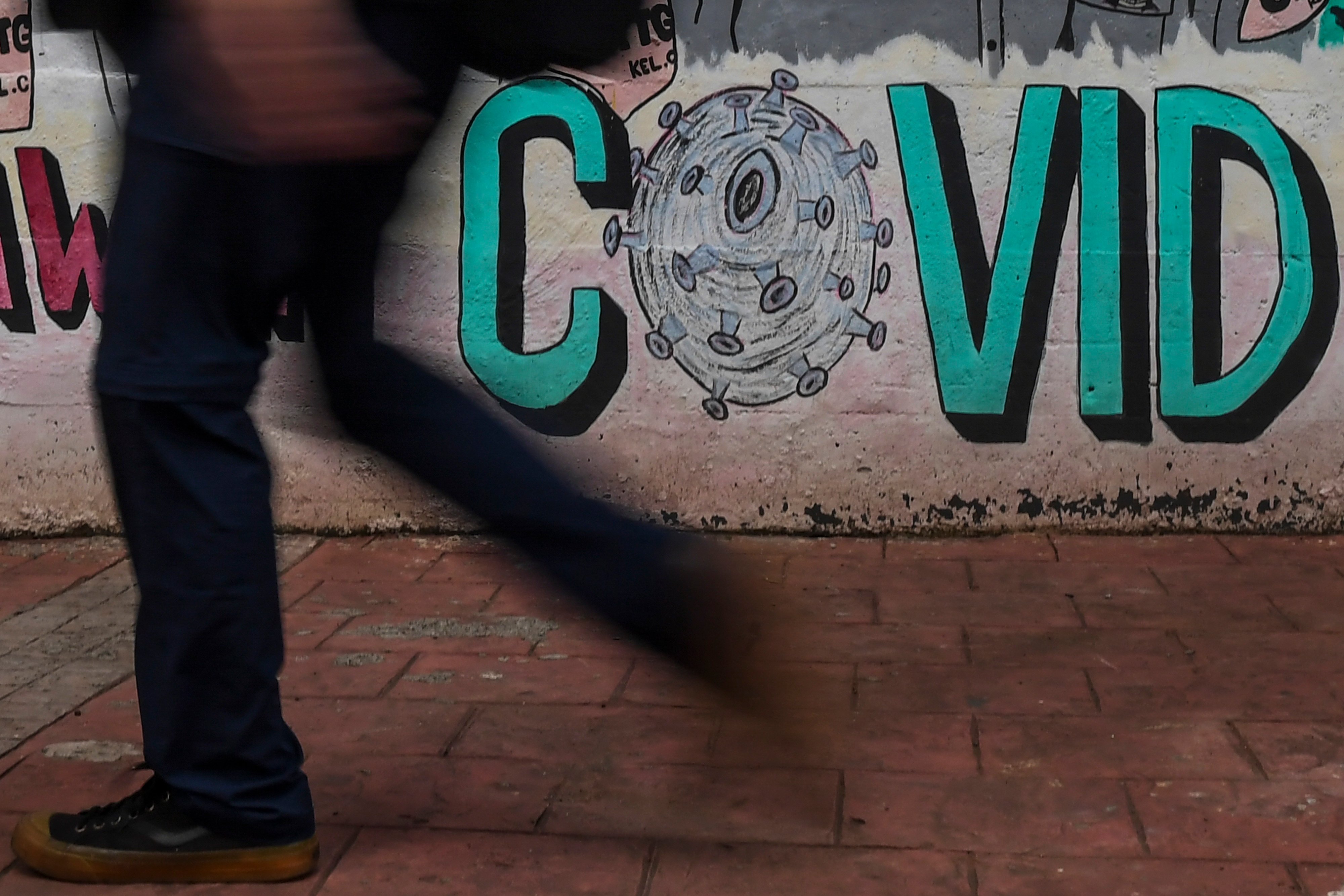 Warga berjalan di dekat mural bertema pencegahan penyebaran COVID-19 di Jakarta, Rabu (2/3/2022).