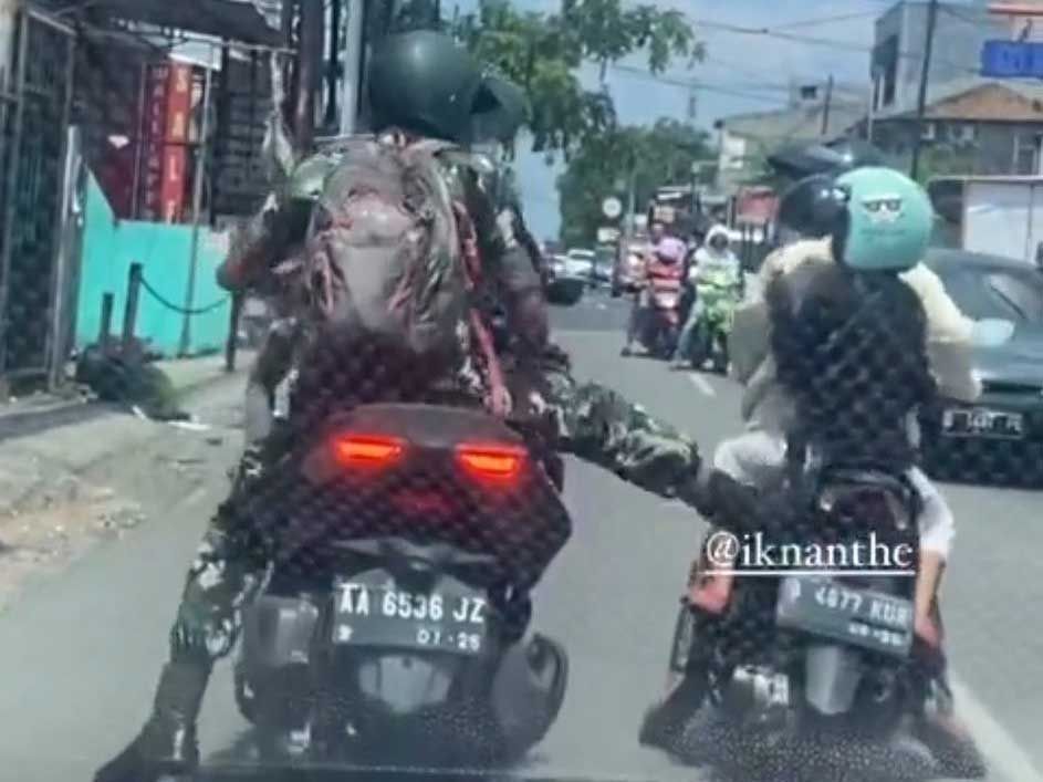 Praka ANG terlihat sedang menendang sebuah sepeda motor yang ditumpangi seorang ibu bersama anaknya.