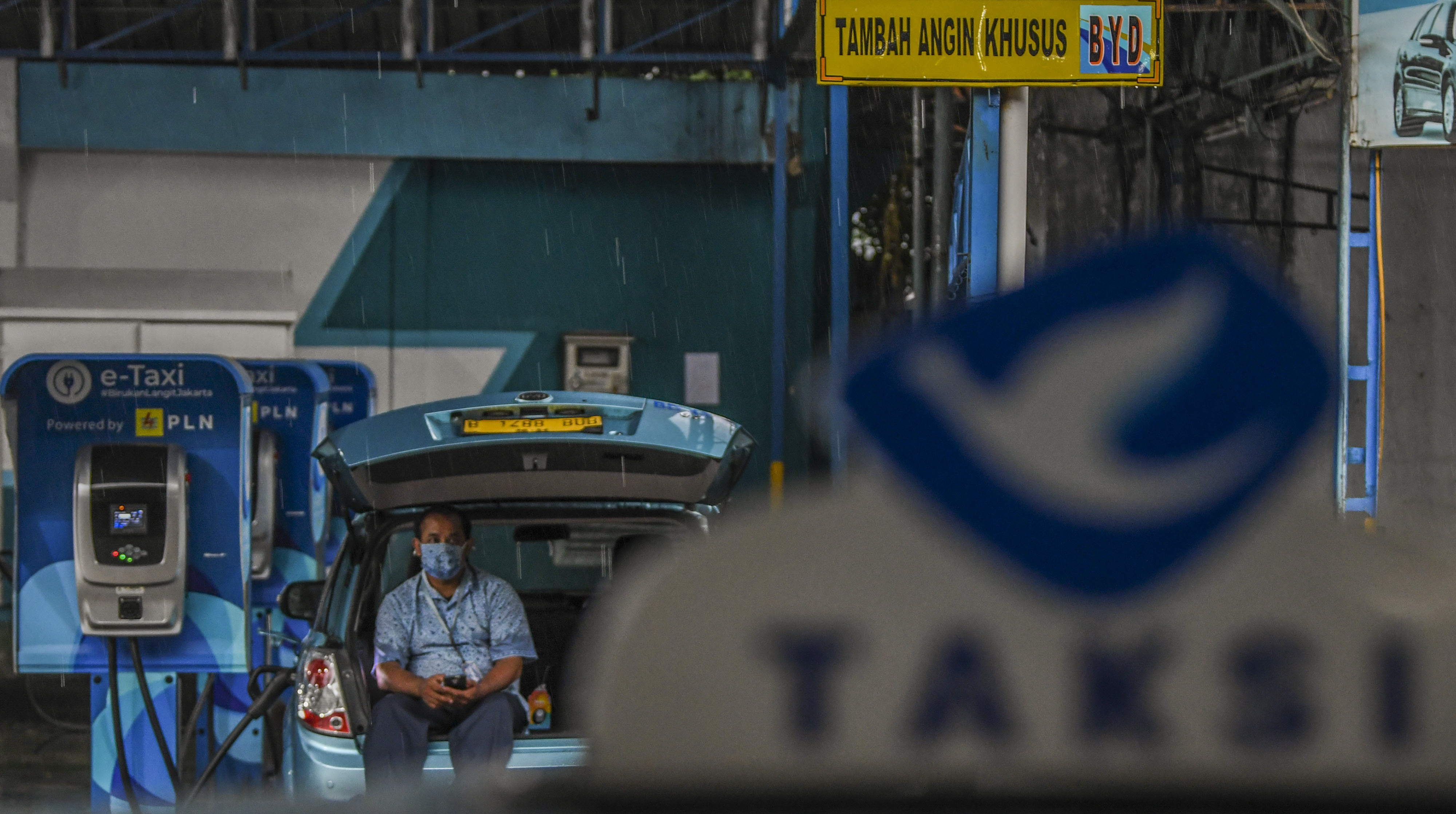 engemudi menunggu pengisian daya mobil taksi listrik Bluebird (e-Taxi) di Kantor Pusat Bluebird Group