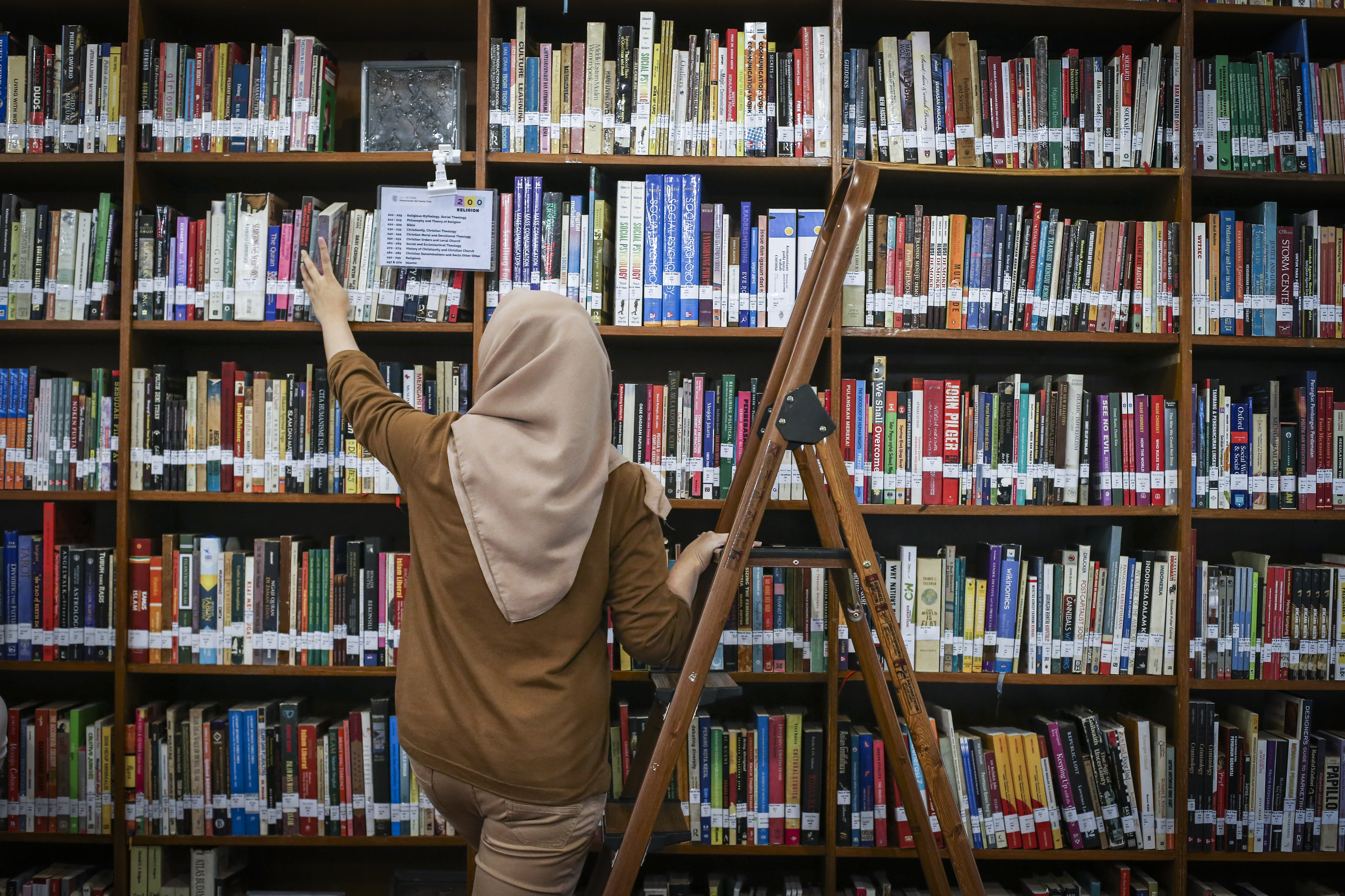 Pengunjung mengambil buku di perpustakaan.