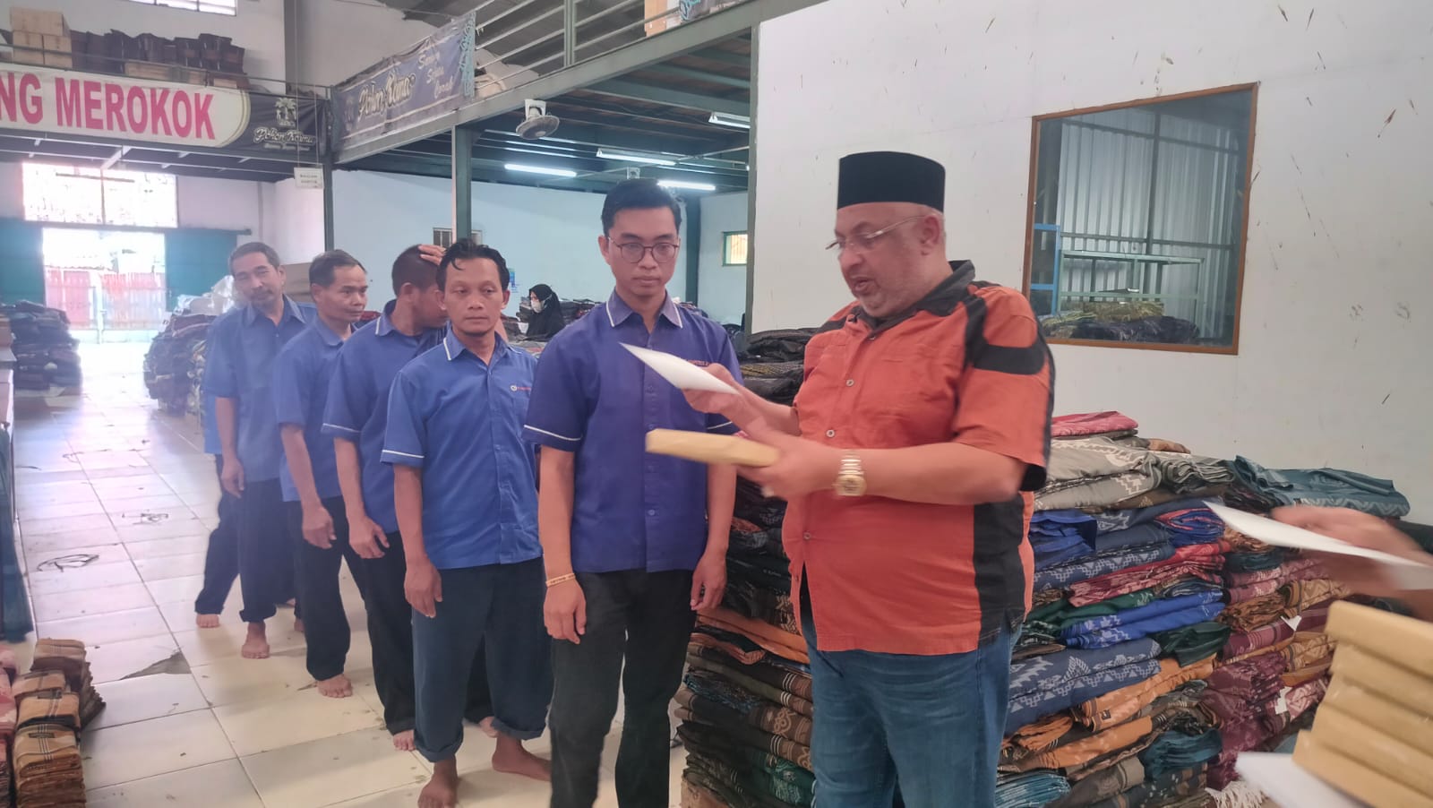Pengusaha kain sarung di Kota Tegal, Jamaludin, sedang memberikan THR dan bingkisan Lebaran kepada sejumlah karyawannya.