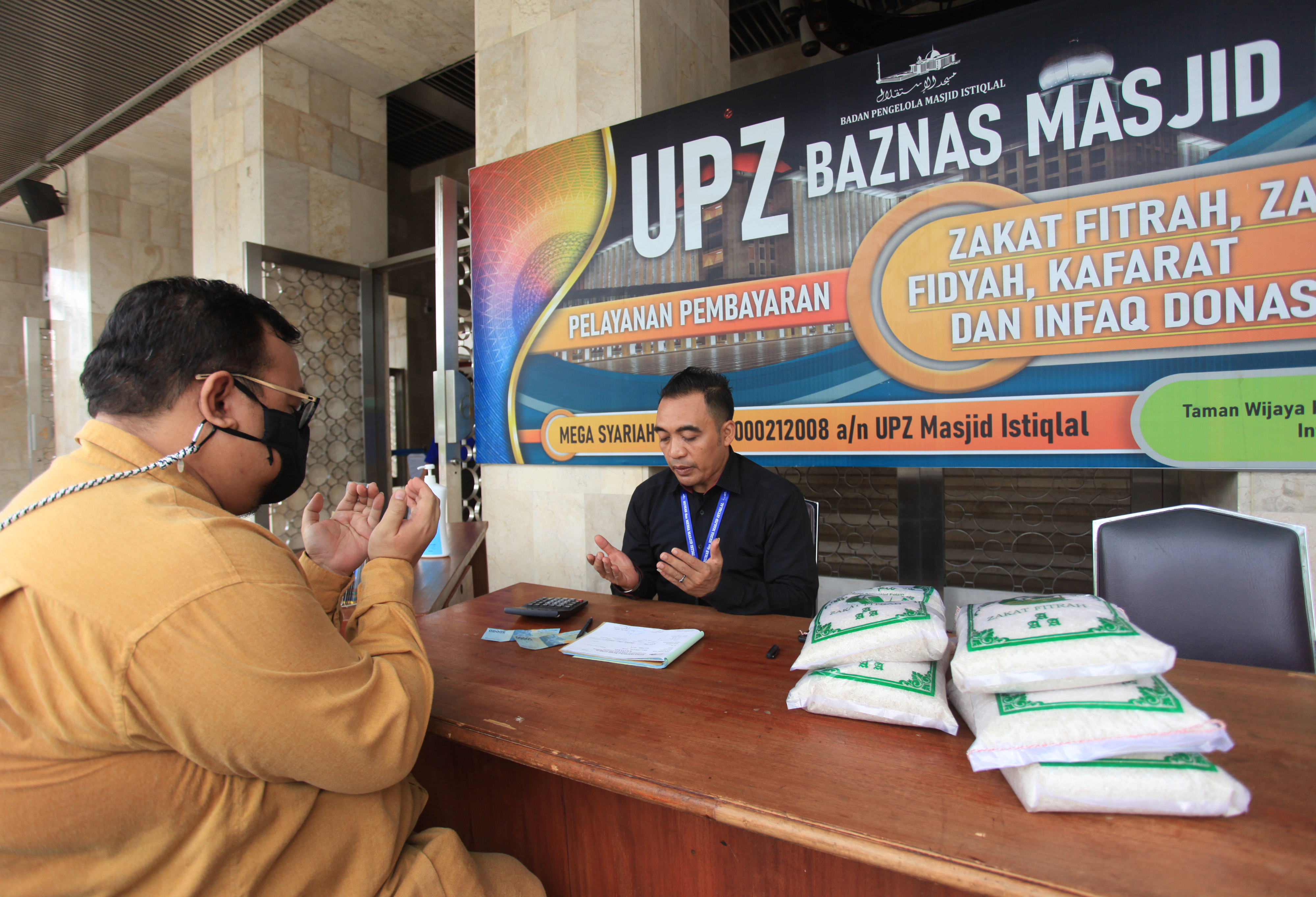 Ilustrasi: petugas amil zakat mendoakan seorang umat Islam yang membayar zakat fitrah