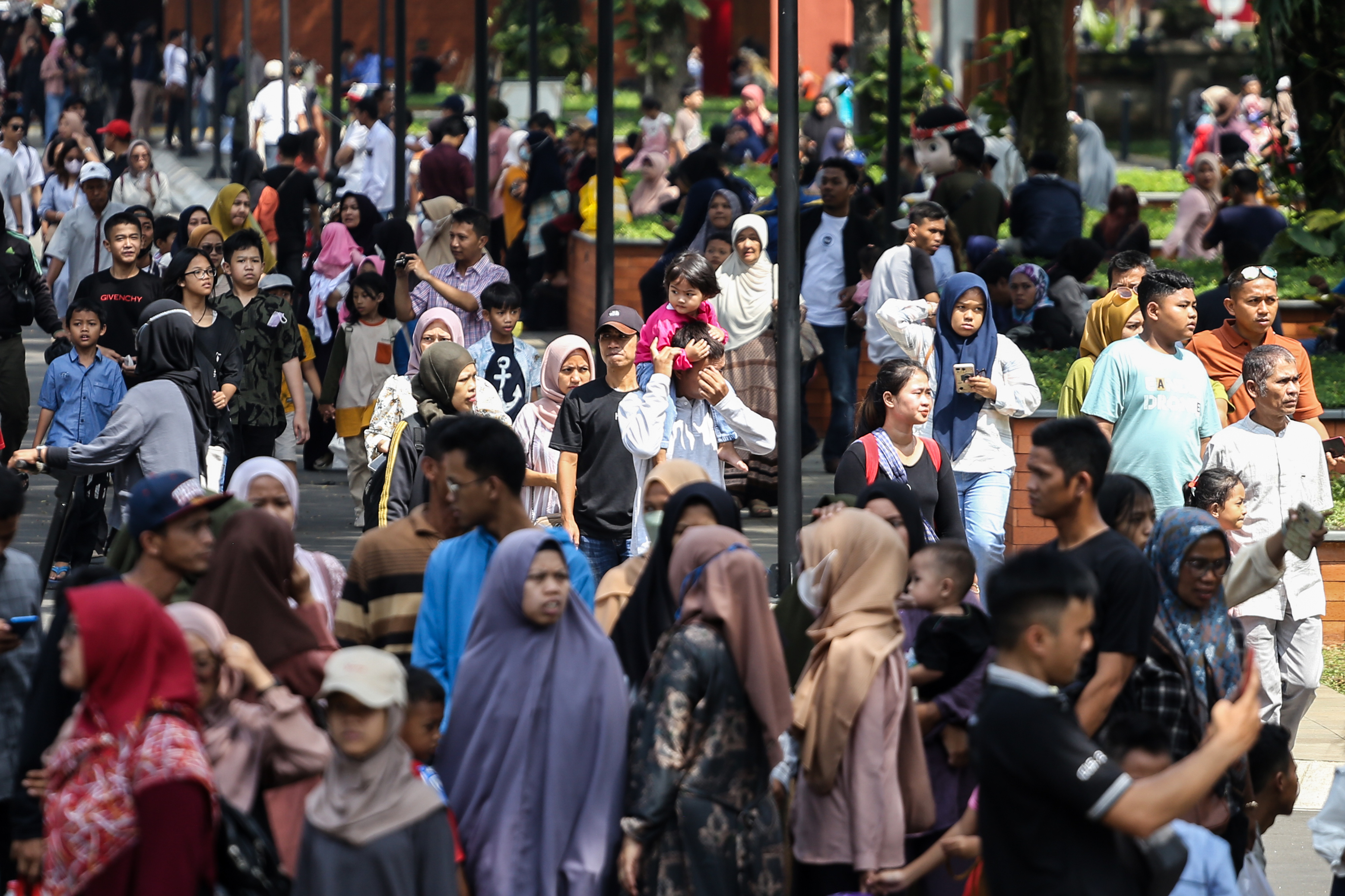 Pengunjung berjalan menuju anjungan di Taman Mini Indonesia Indah (TMII), Jakarta, Minggu (23/4).