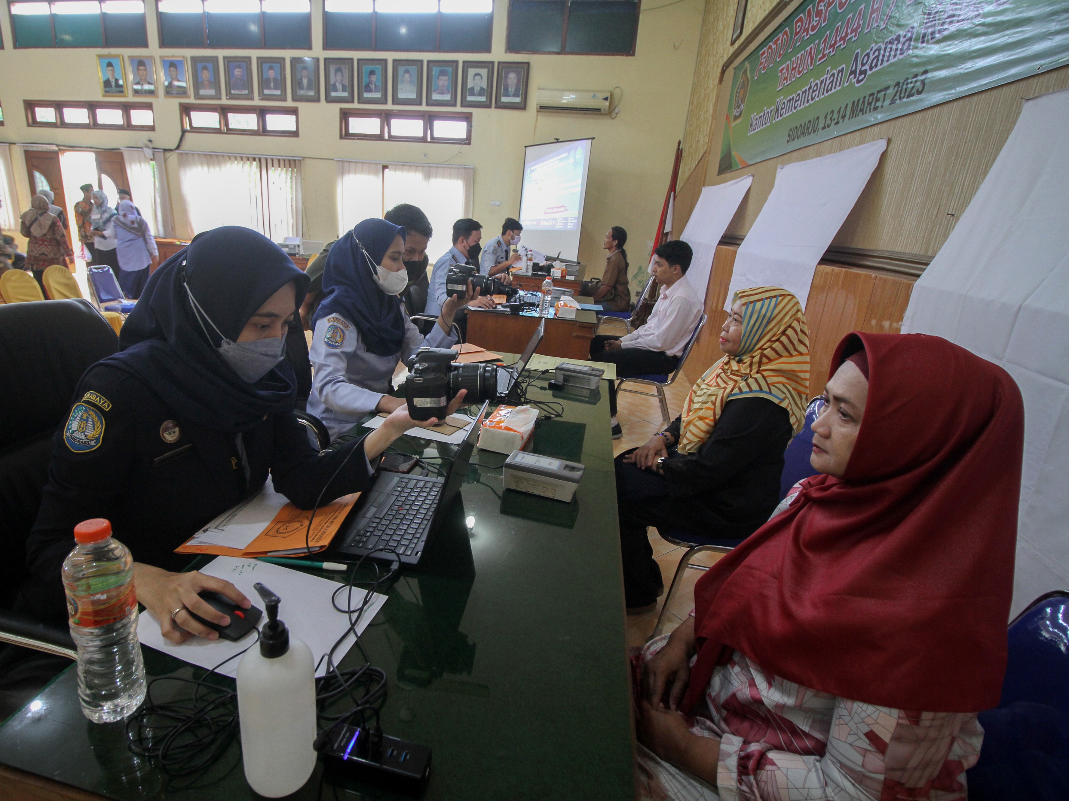 Petugas memotret jemaah calon haji saat melayani pembuatan paspor di Kantor Kemenag Sidoarjo, Jawa Timur, Selasa (14/3/2023). 