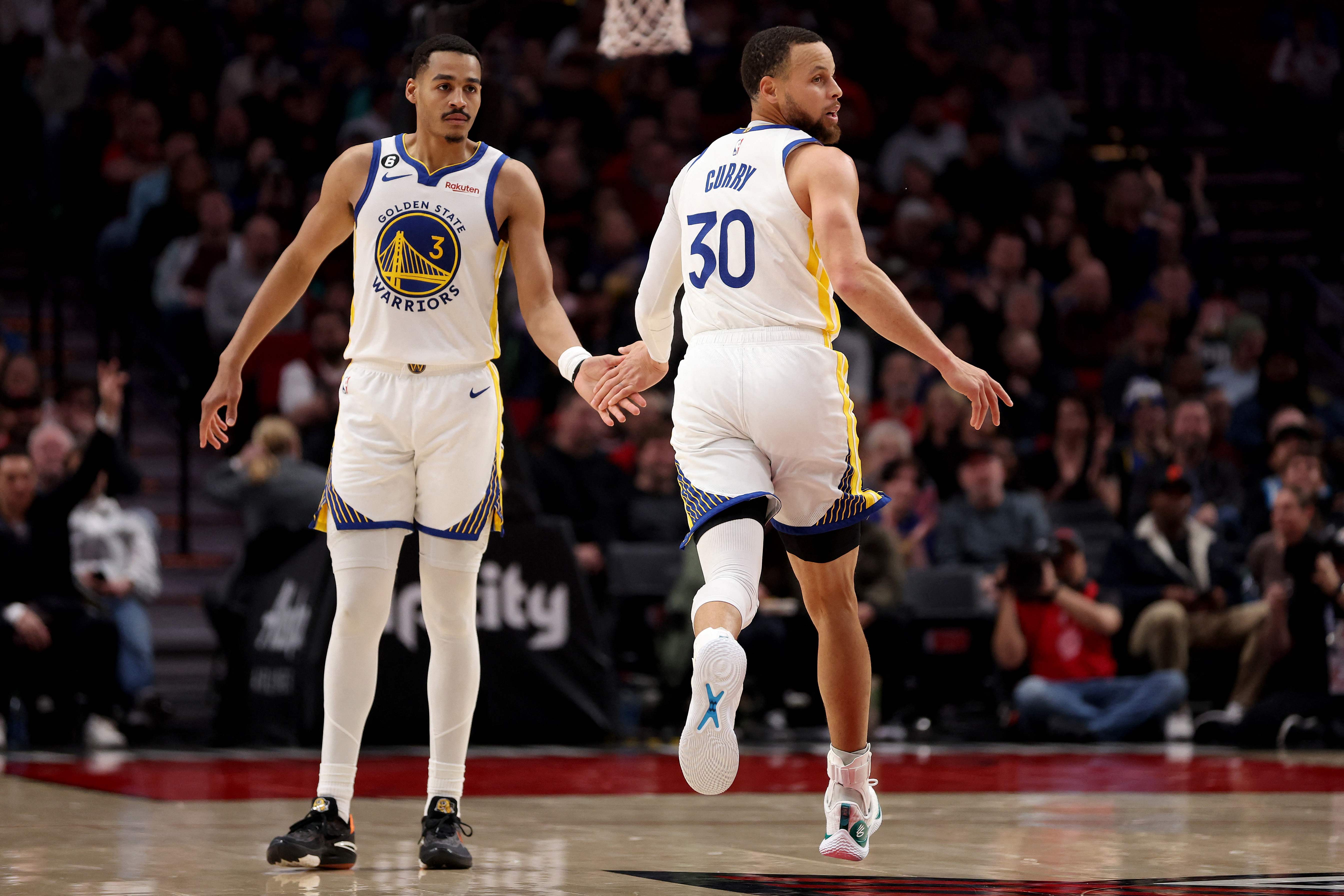 Pemain Golden State Warriors Jordan Poole (kiri) dan rekan setimnya Stephen Curry.