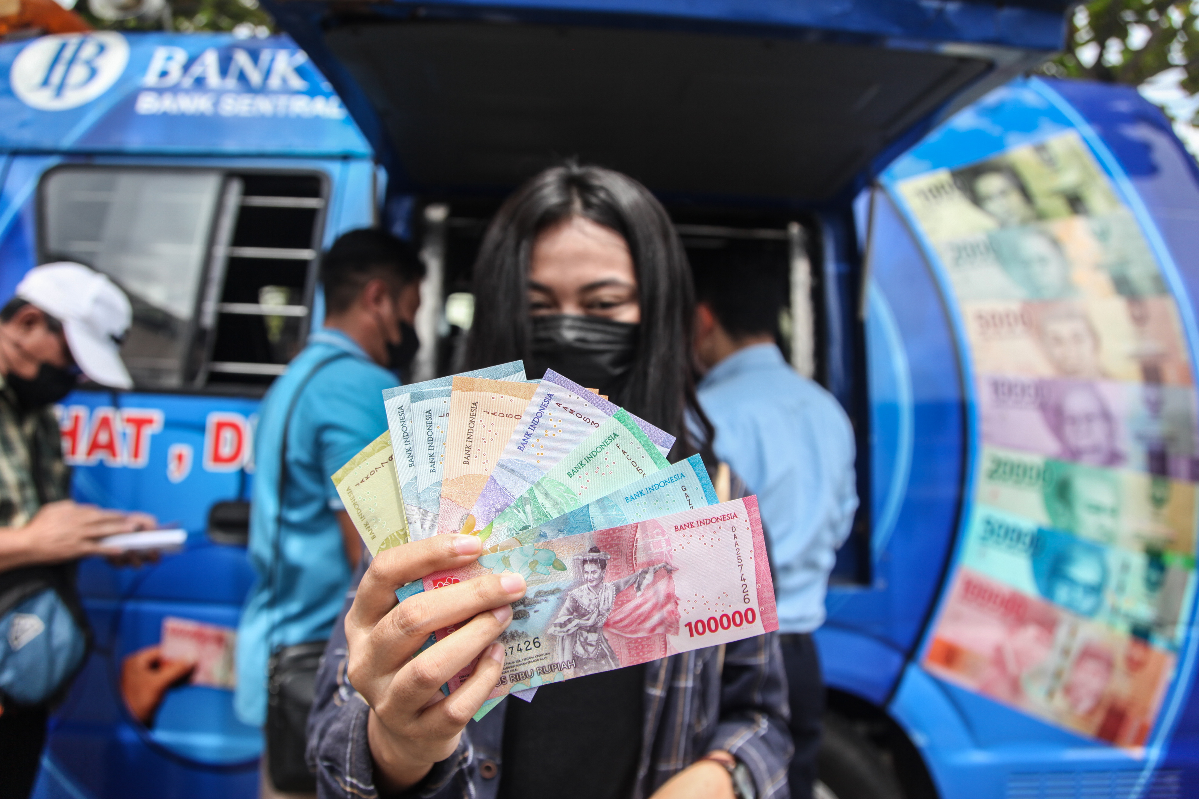 Warga memperlihatkan uang Rupiah kertas terbaru usai menukarkan di mobil kas 