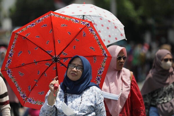 Pengunjung Kota Tua melindungi diri dari cuaca panas ekstrem.