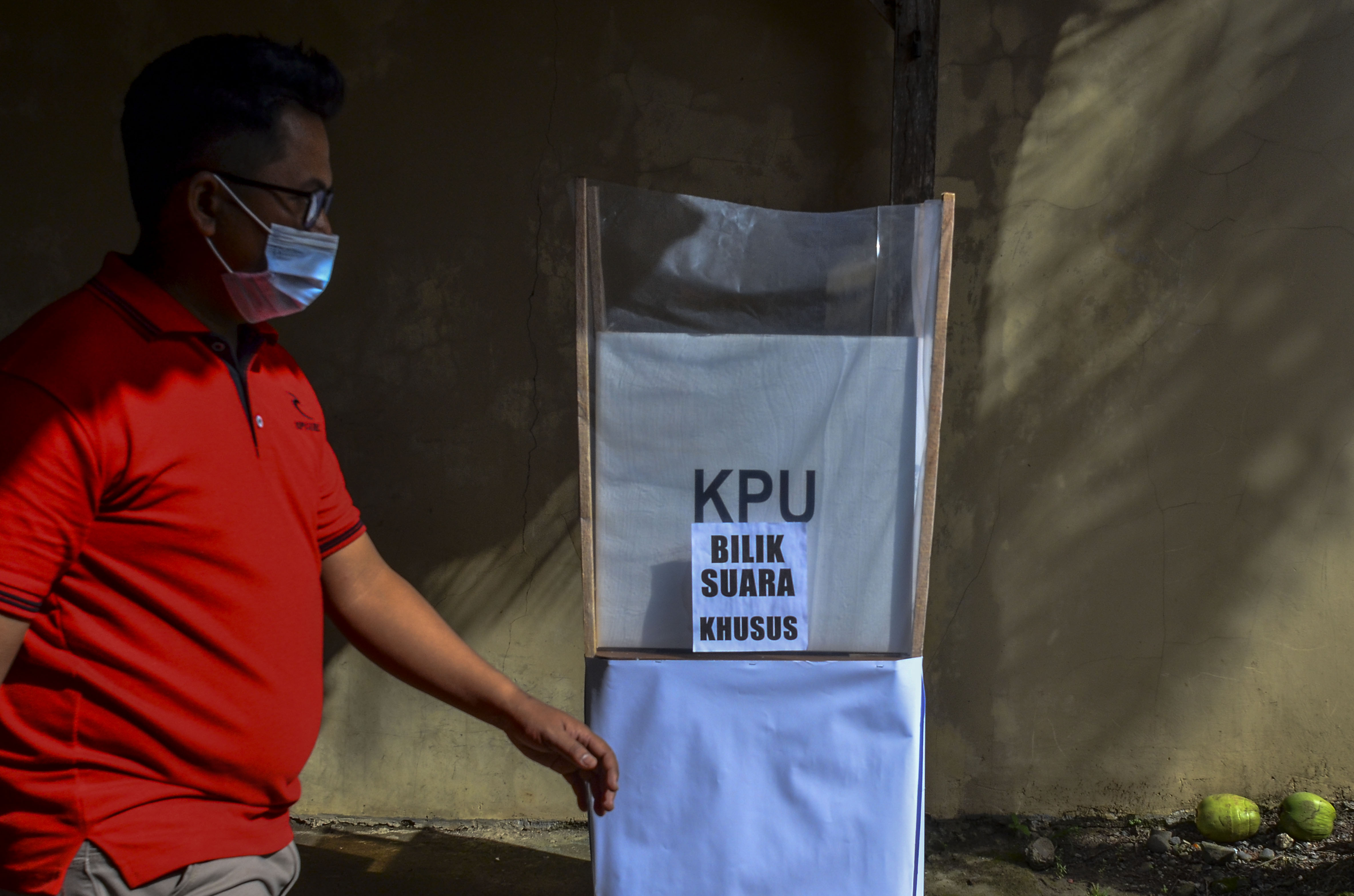 Warga melintas di dekat bilik suara khusus di TPS 02, Desa Pananjung, Kabupaten Pangandaran, Jawa Barat, Rabu (9/12/2020).