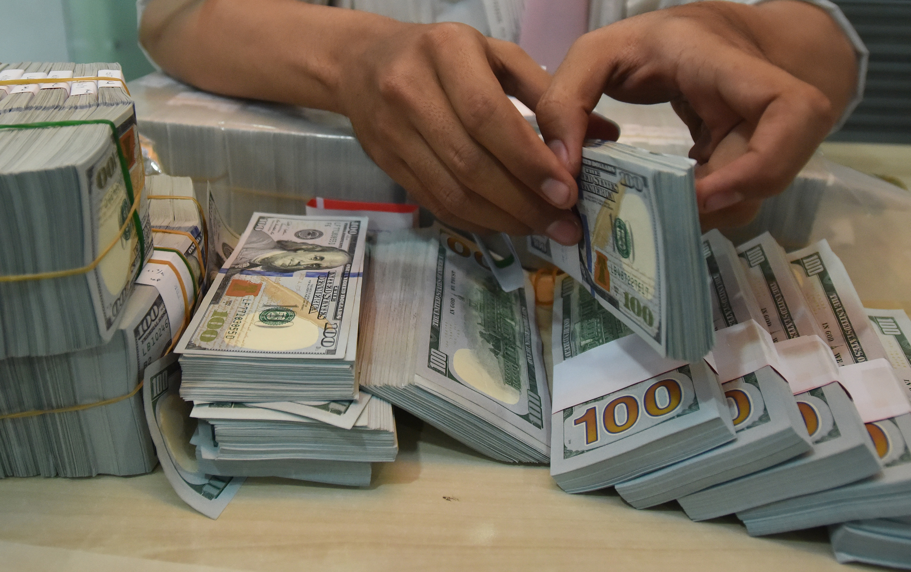 Petugas menghitung uang dollar AS.