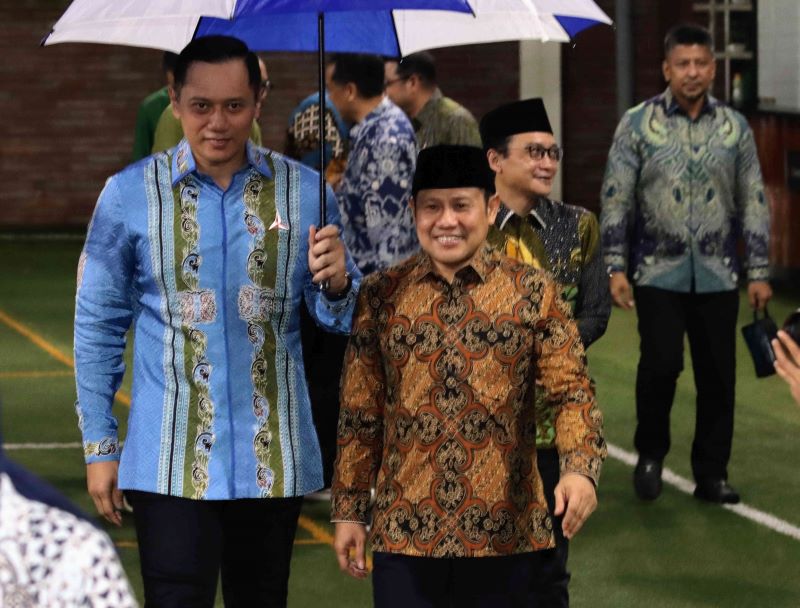 Ketua Umum Partai Demokrat AHY memayungi Ketua Umum PKB Muhaimin Iskandar selepas pertemuan di Puri Cikeas, Bogor.