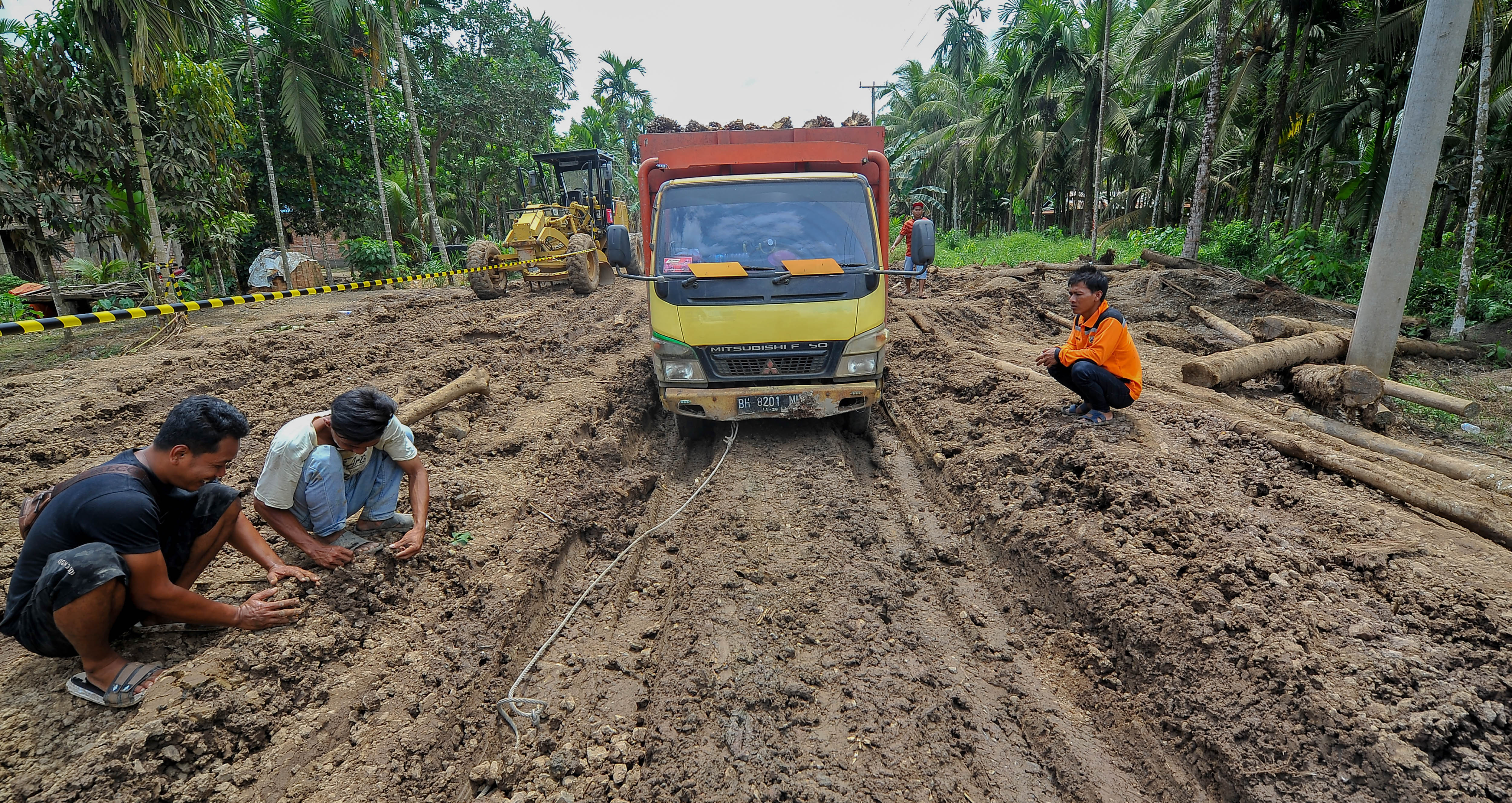 Pengemudi menunggu mobil penarik untuk mengeluarkan truk yang terperosok di jalan lintas Jambi-Nipah Panjang yang rusak di Muara Sabak Ulu