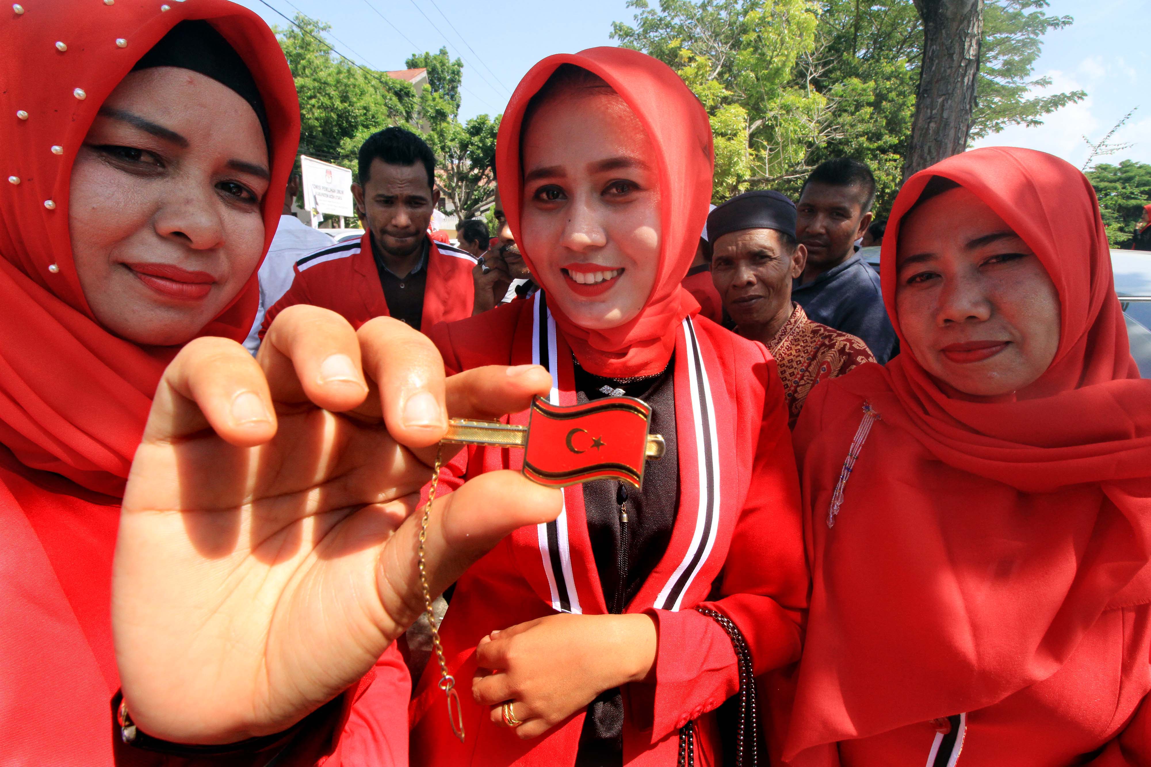 Bakal Calon Legislatif (bacaleg) perempuan dari Partai Aceh (PA) menunjukkan pin partai usai mendaftar di kantor Komisi Independen Pemilihan
