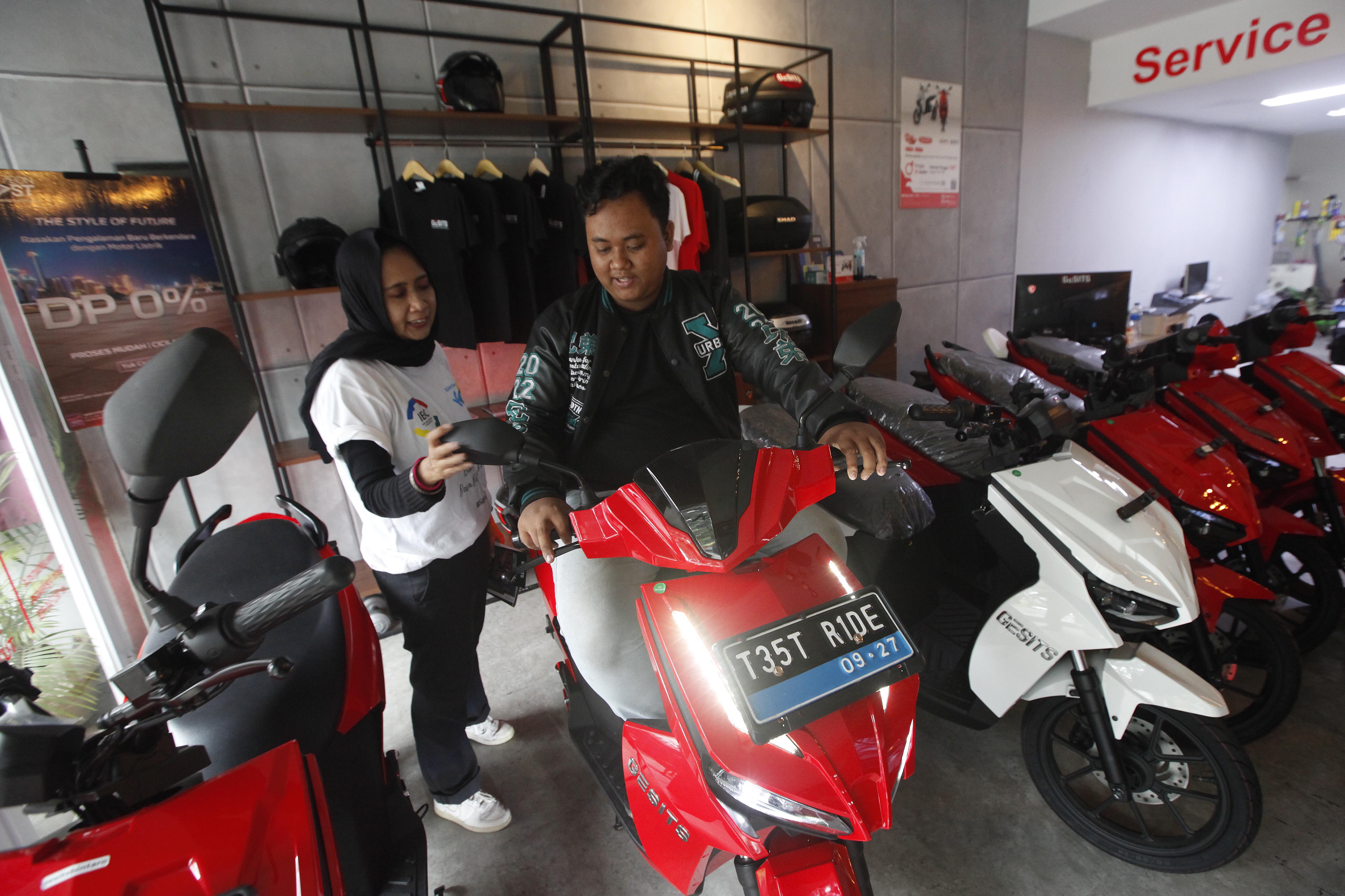 Tenaga penjual memberikan edukasi kepada calon pembeli terkait produk kendaraan listrik di diler motor listrik Gesits di kawasan Bintaro.