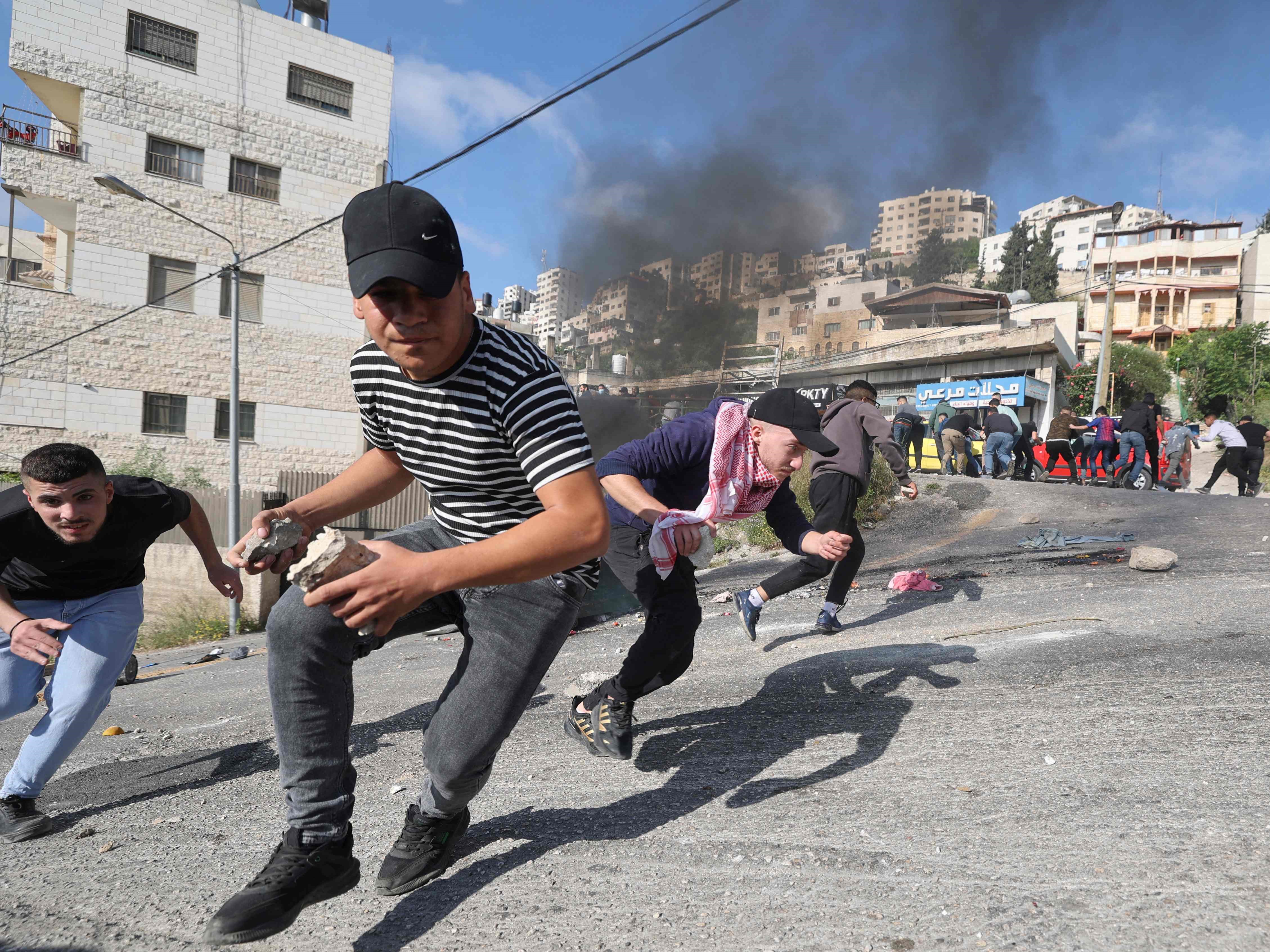 Pengunjuk rasa Palestina berlindung di tengah bentrokan dengan pasukan keamanan Israel selama penggerebekan di kota tua Nablus, Tepi Barat.