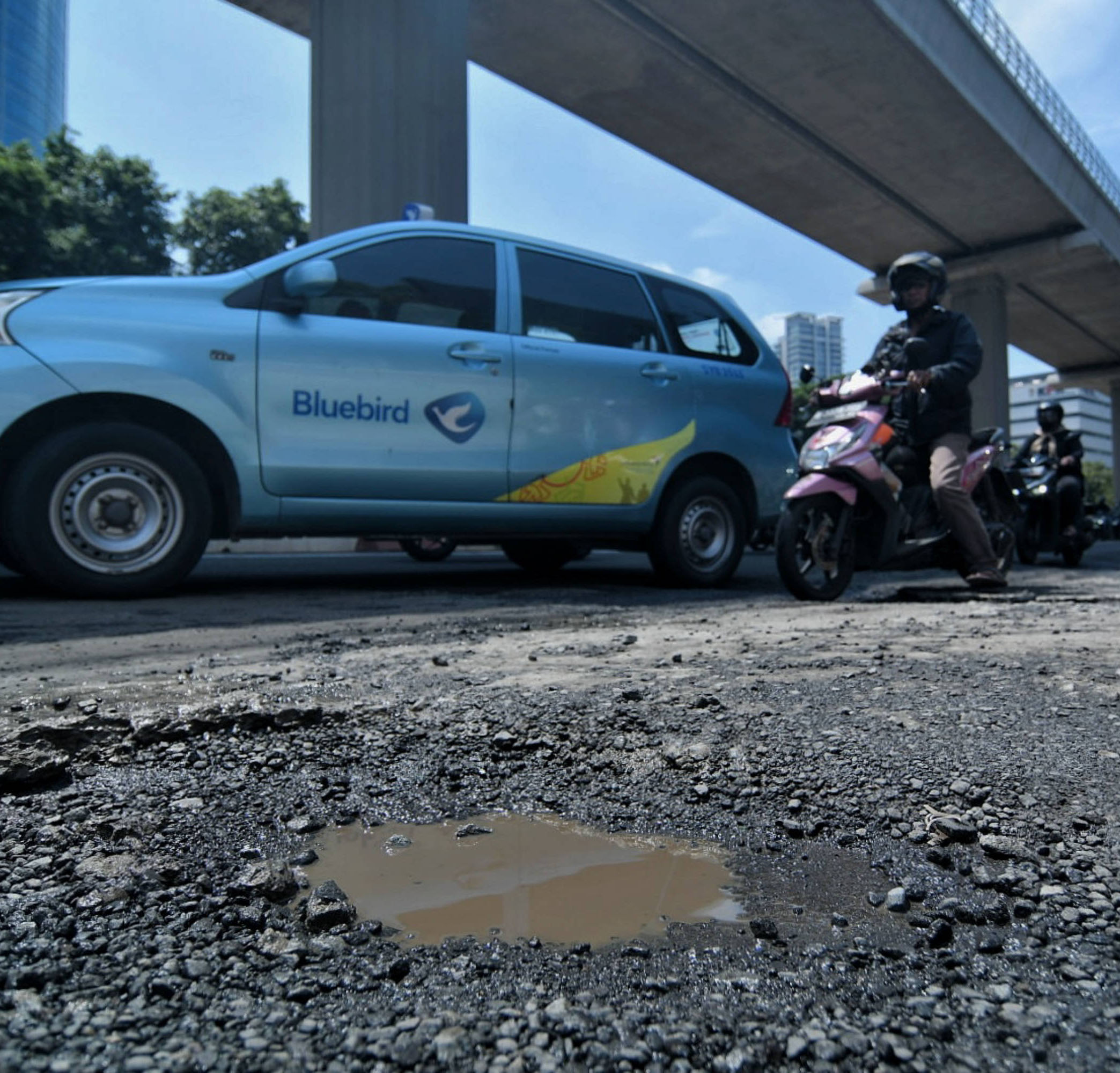 Pengendara melintasi Jalan Rasuna Said yang rusak di Jakarta, Senin (14/3/2022)