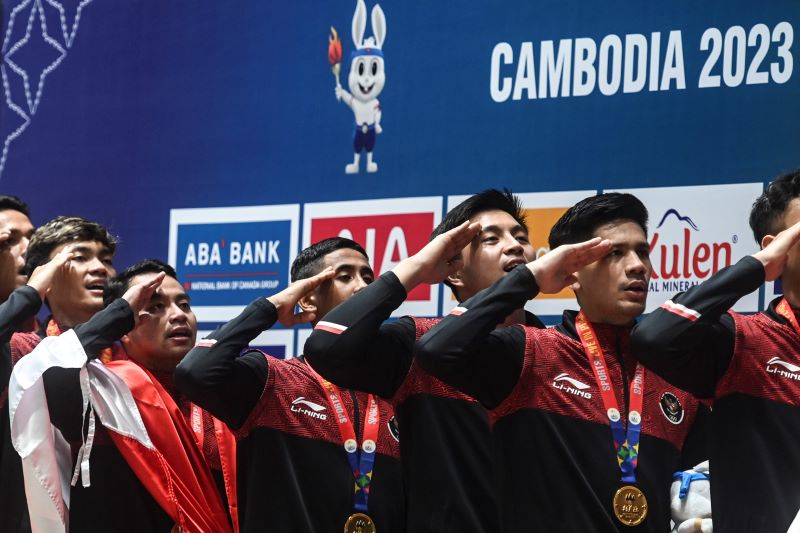 Atlet bulu tangkis putra Indonesia memberi penghormatan kepada bendera Merah Putih saat upacara pemberian medali emas.