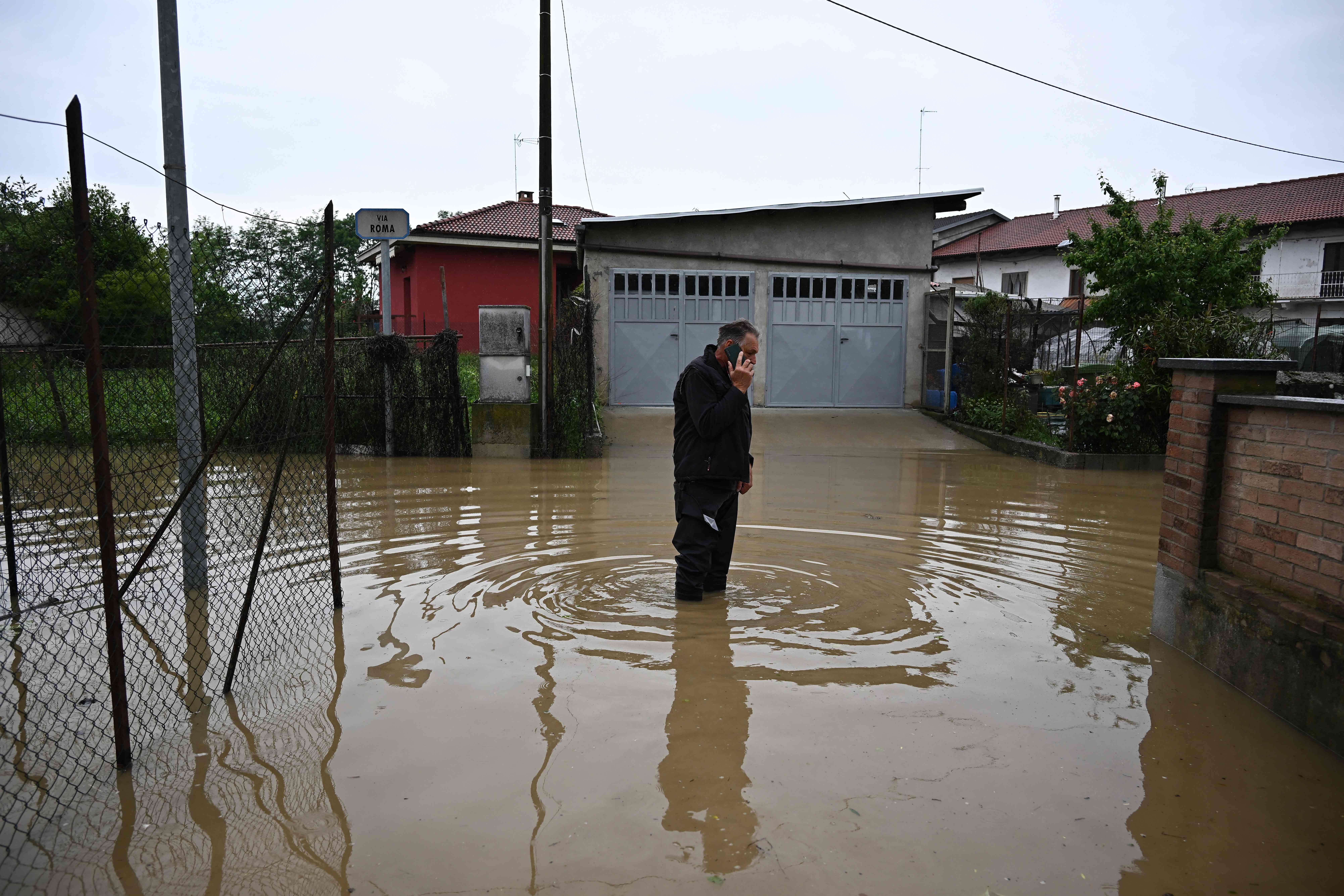 Warga Italia berusaha melewati genangan air banjir yang melanda wilayah mereka
