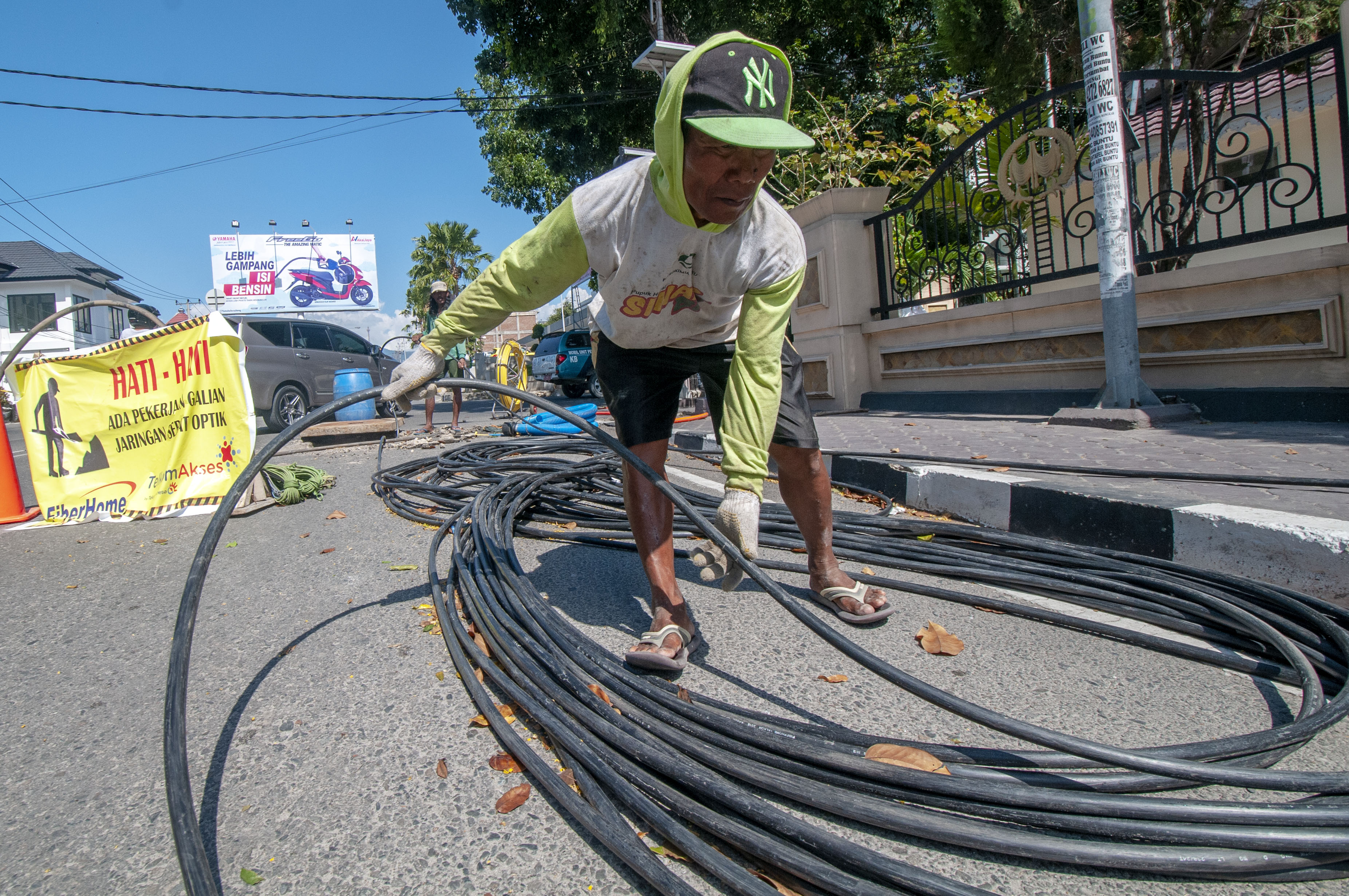 Pekerja merapikan kabel serat optik di Makassar.