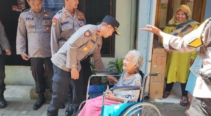 Komisaris Muhammad Fadlan menyerahkan kursi roda pada seorang warga. 