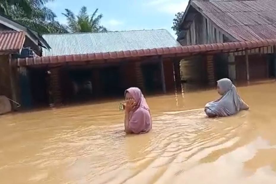 Dua warga berjalan melalui banjir, Aceh Barat.