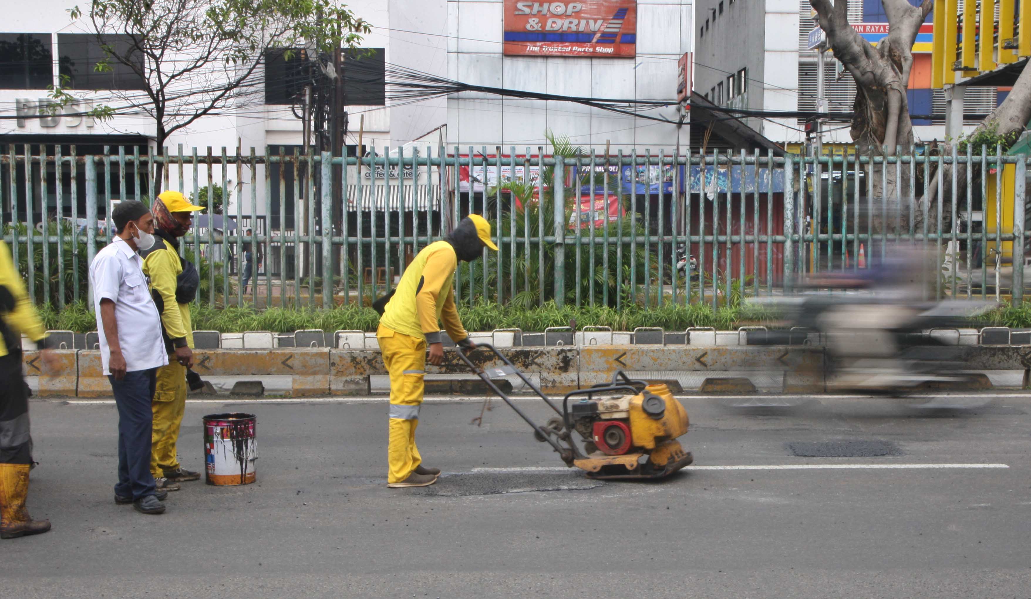 Petugas memperbaiki jalan rusak di Jakarta