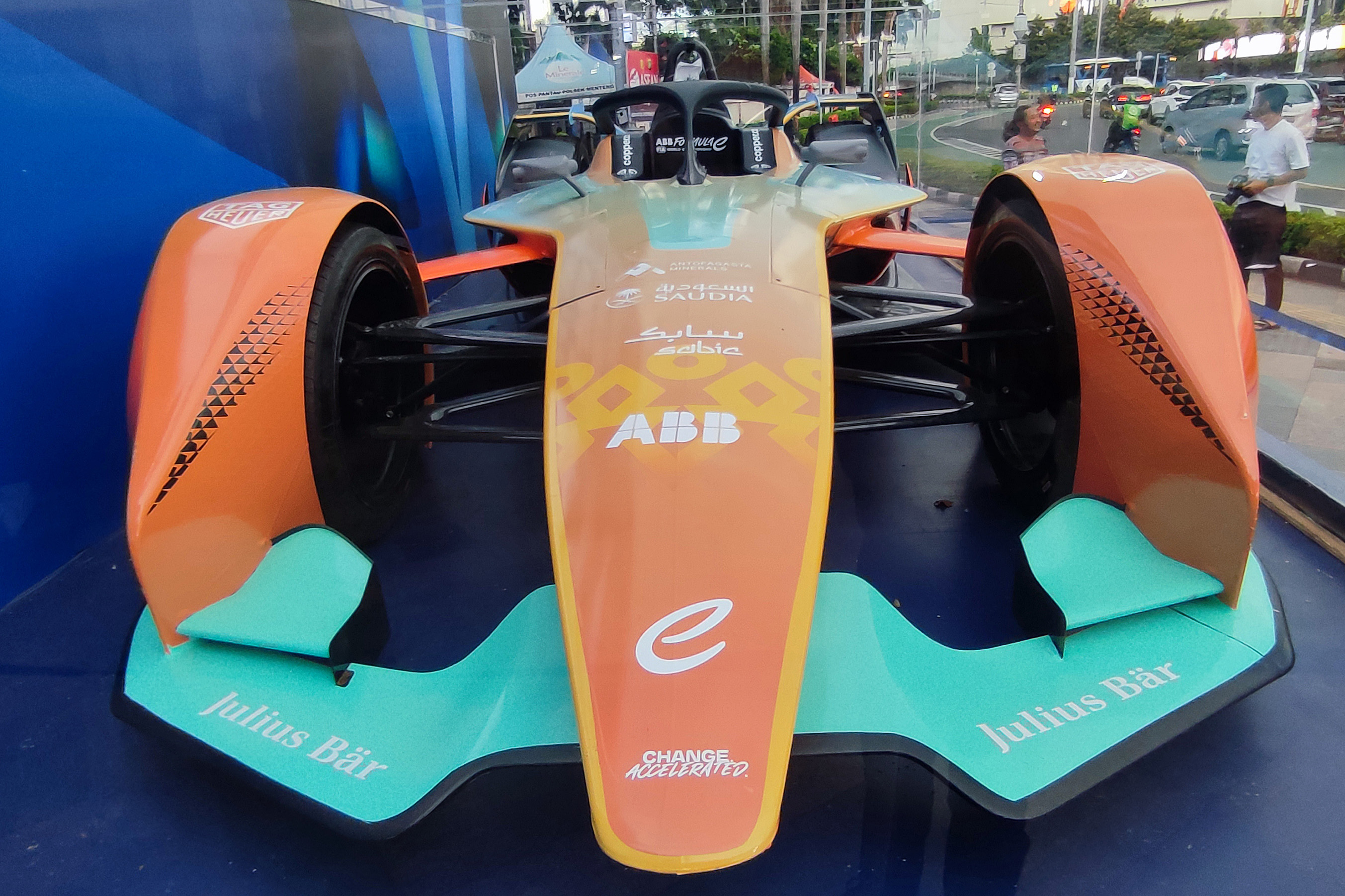 Masyarakat melintas di depan mobil balap Formula E di Bundaran HI, Jakarta,