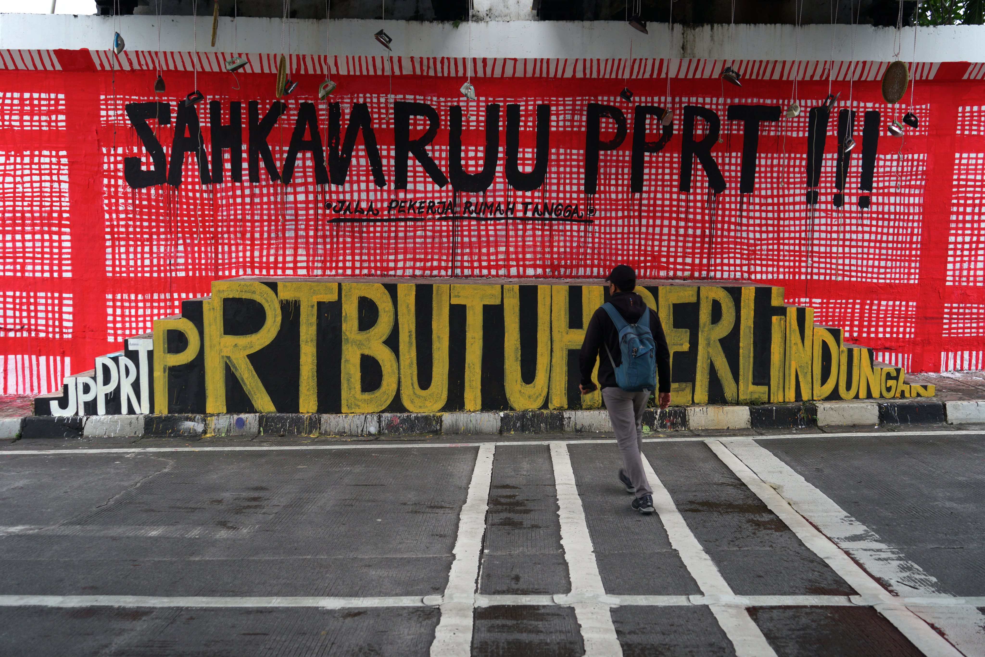 Warga melintas di dekat mural yang bertuliskan 