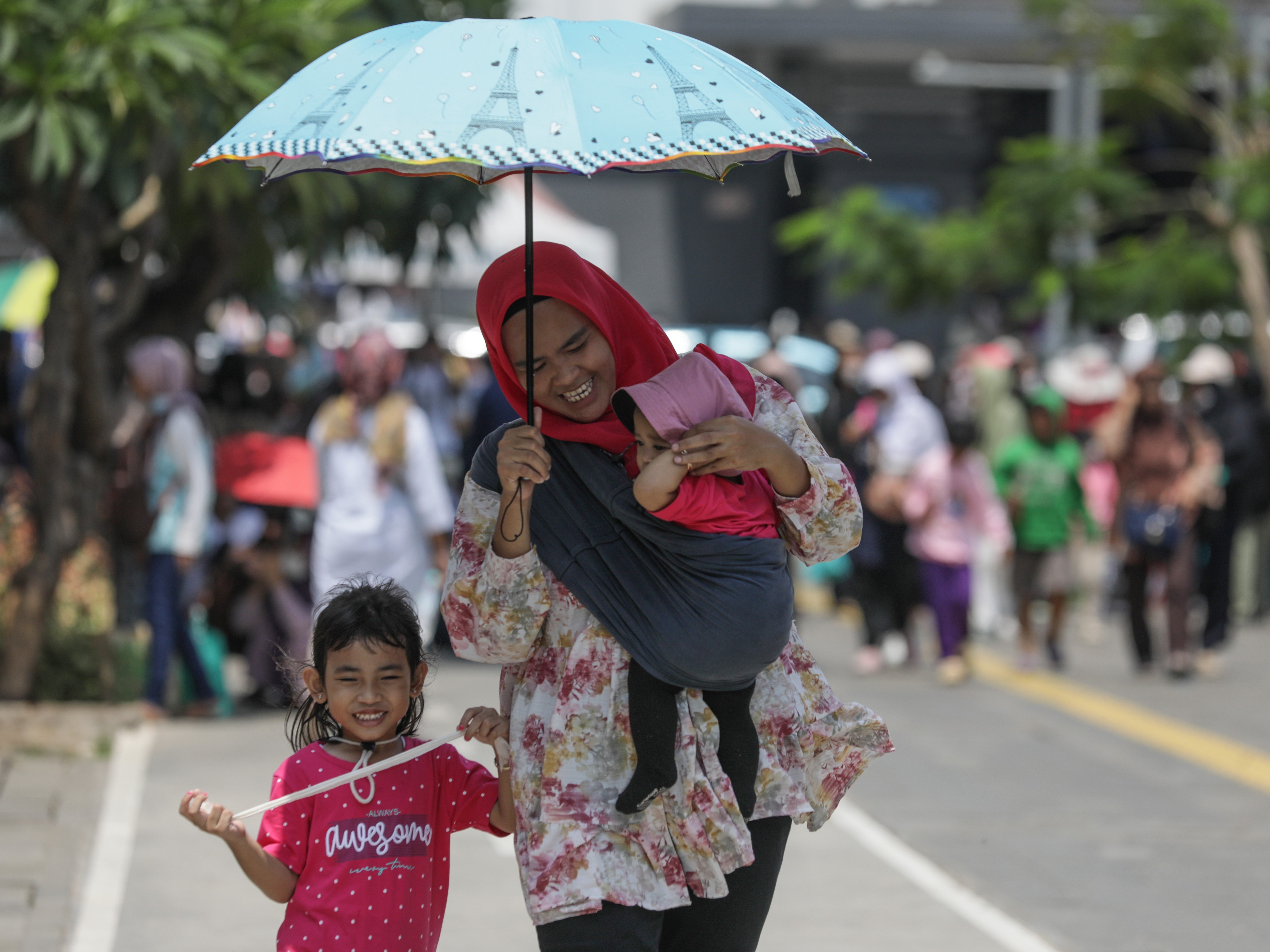 Pengunjung menggunakan payung untuk berlindung dari sengatan sinar matahari saat mengunjungi tempat wisata Kota Tua, Jakarta.