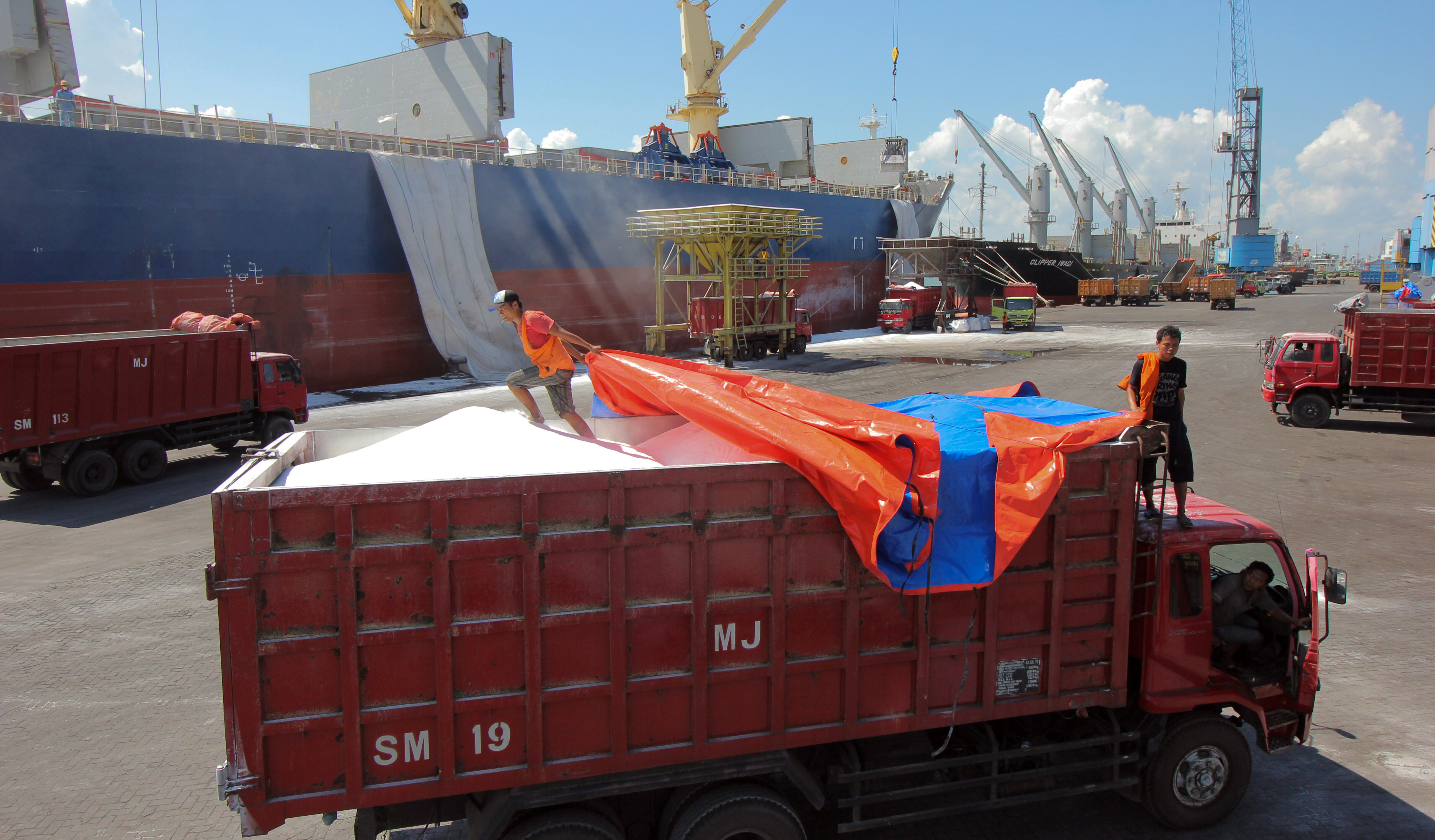 Kernet menutup muatan Soda Ash dengan terpal di dermaga Jamrud Utara, Pelabuhan Tanjung Perak, Surabaya, Jawa Timur.