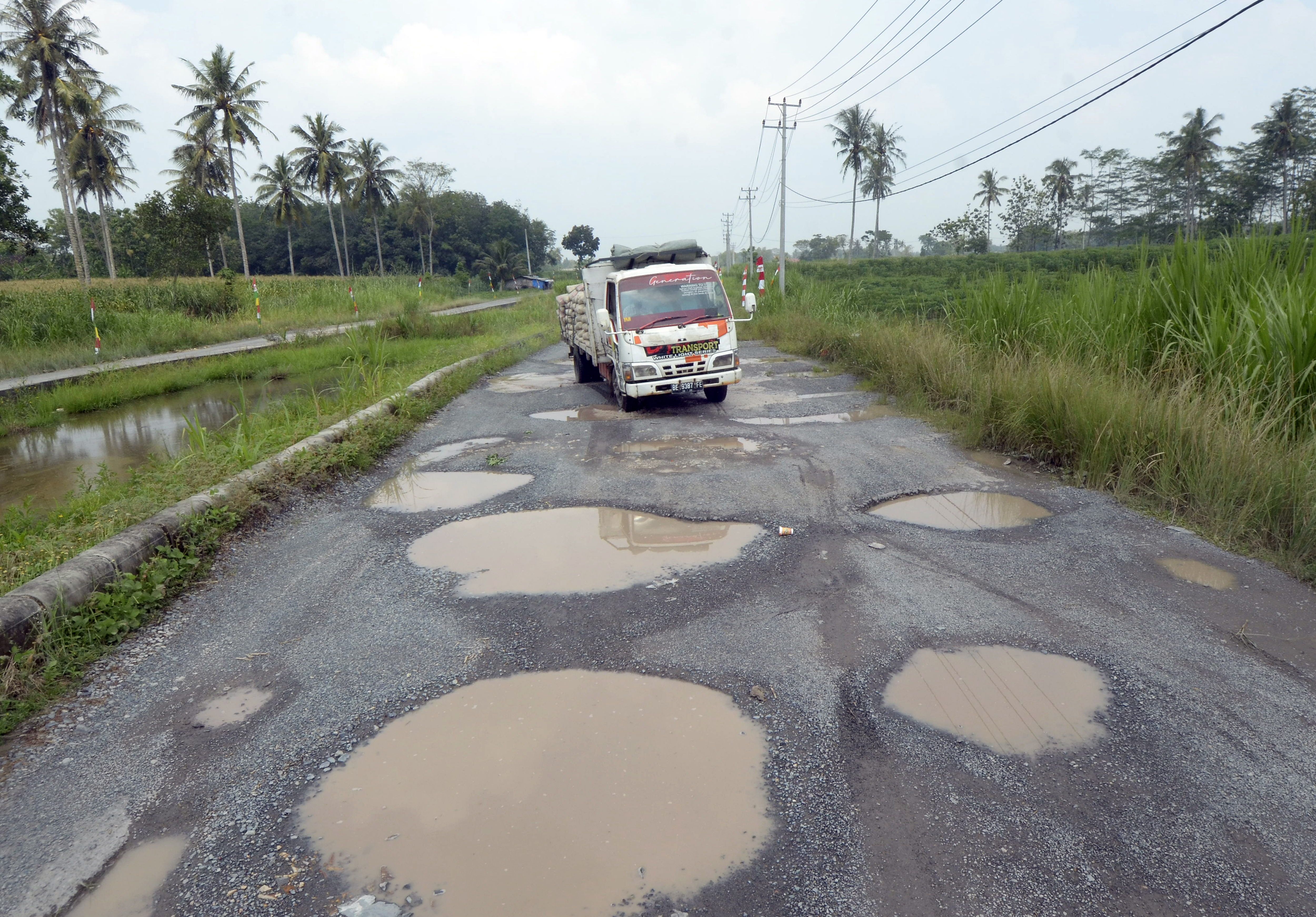 Mobil melintas di antara jalan berlubang yang tergenang air di jalan terusan Ryacudu Jati Agung, Lampung Selatan, Lampung, Rabu (3/5).