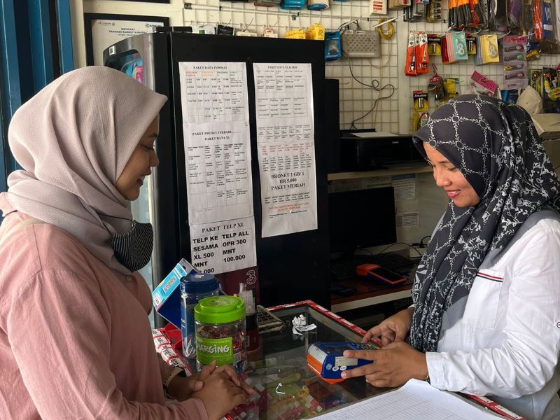 Netra Novera (kanan) sedang melayani pelanggan yang hendak membayar tagihan