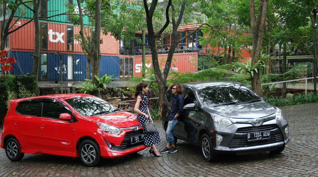 Model berpose dengan latar mobil Toyota Calya dan Agya.