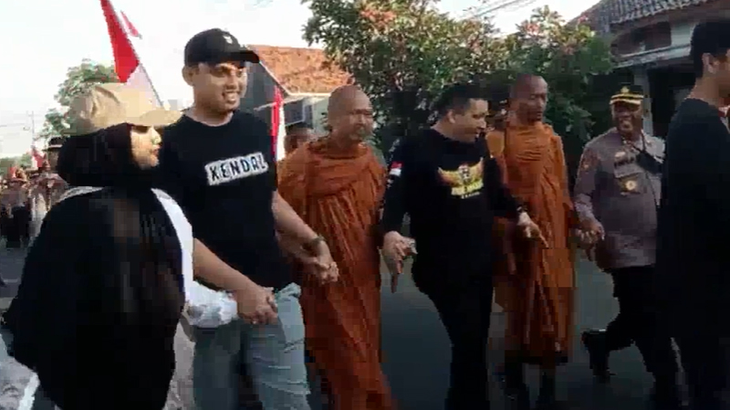 Bupati Kendal berjalan bergandengan tangan dengan biksu yang menjalankan prosesi thudong menuju Candi Borobudur.