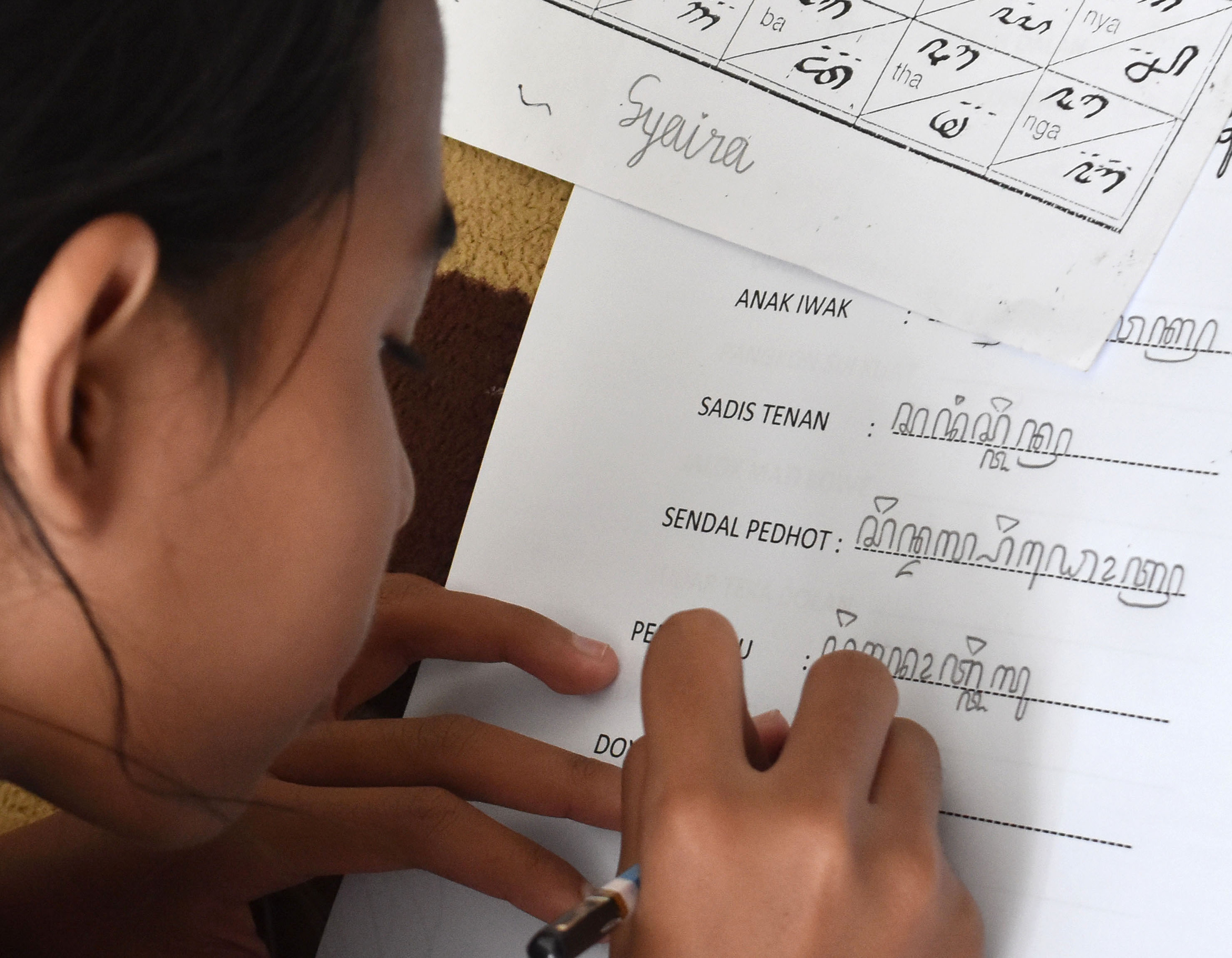 Seorang anak yang menulis aksara jawa kuno.