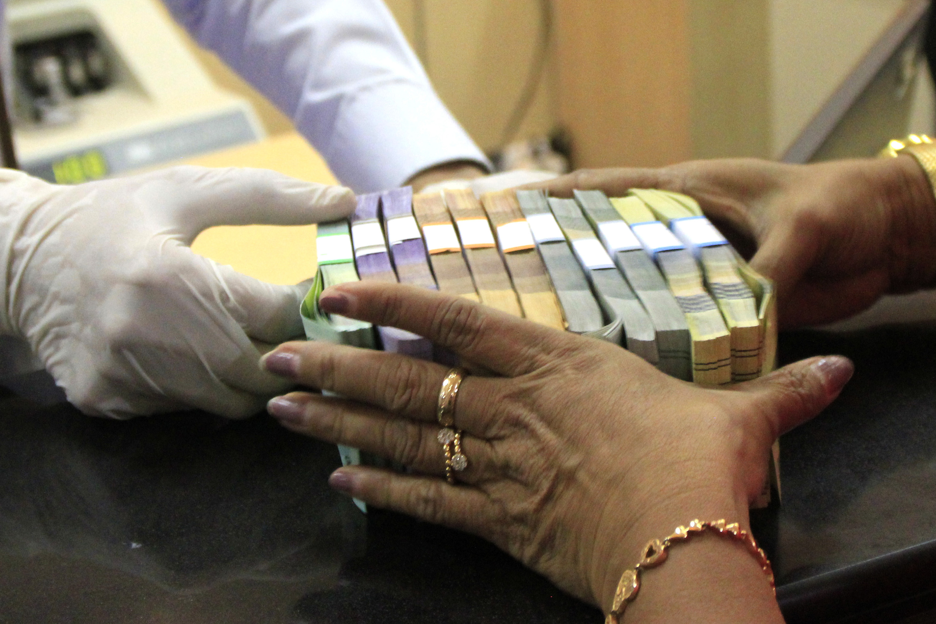 Petugas bank menyerahkan uang rupiah kepada nasabah.