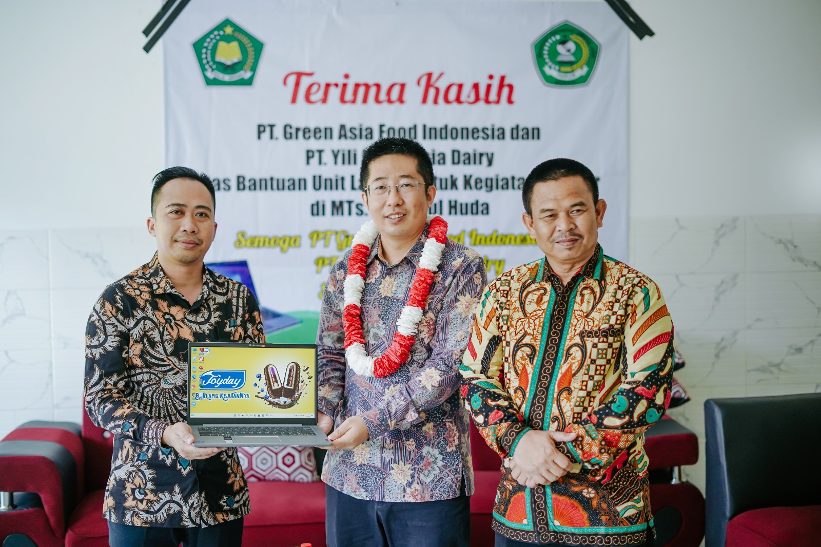  Presiden Direktur Yili Indonesia Dairy, Yu Miao, menyerahkan lapkop kepada  Kepala Sekolah Madrasah Tsanawiyah Jamiatul Huda, Ahwaludin. 