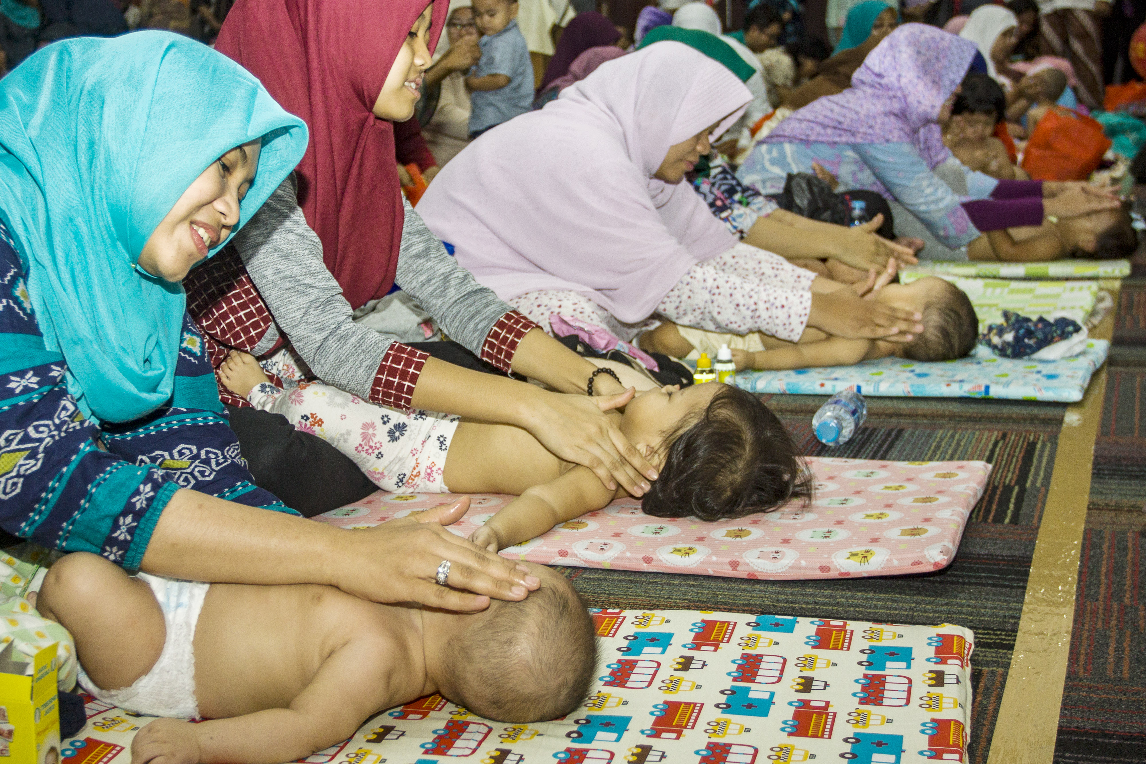 Peserta pijat bayi memijat anaknya saat kegiatan pijat bayi massal di Kementerian Kesehatan, Jakarta.